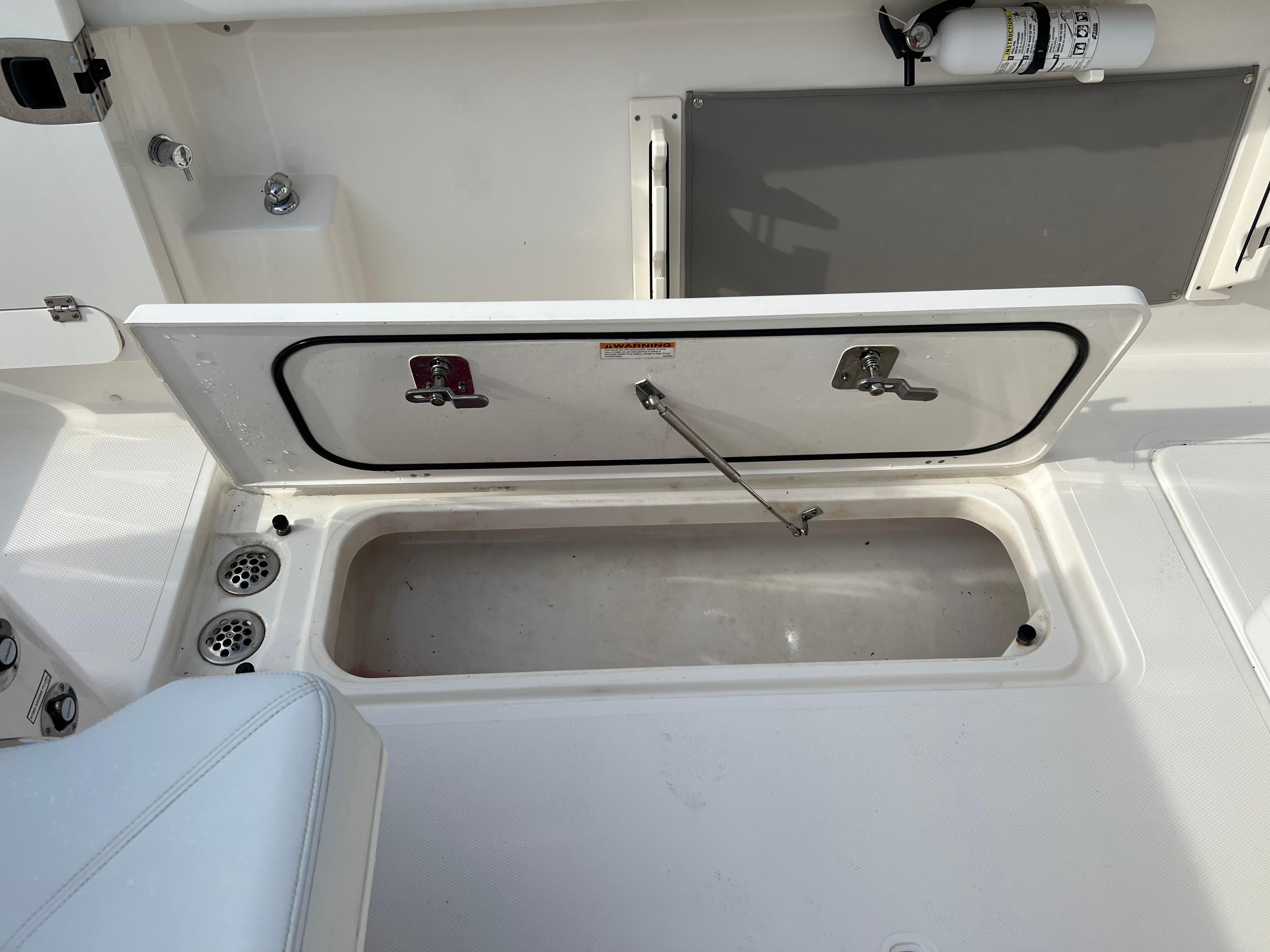 2022 Pursuit S 358 boat storage compartment with open hatch and fire extinguisher.