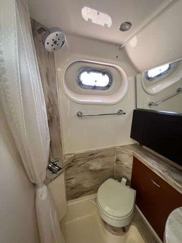 2019 Pursuit S 408 Sport boat bathroom with shower, toilet, and porthole window.