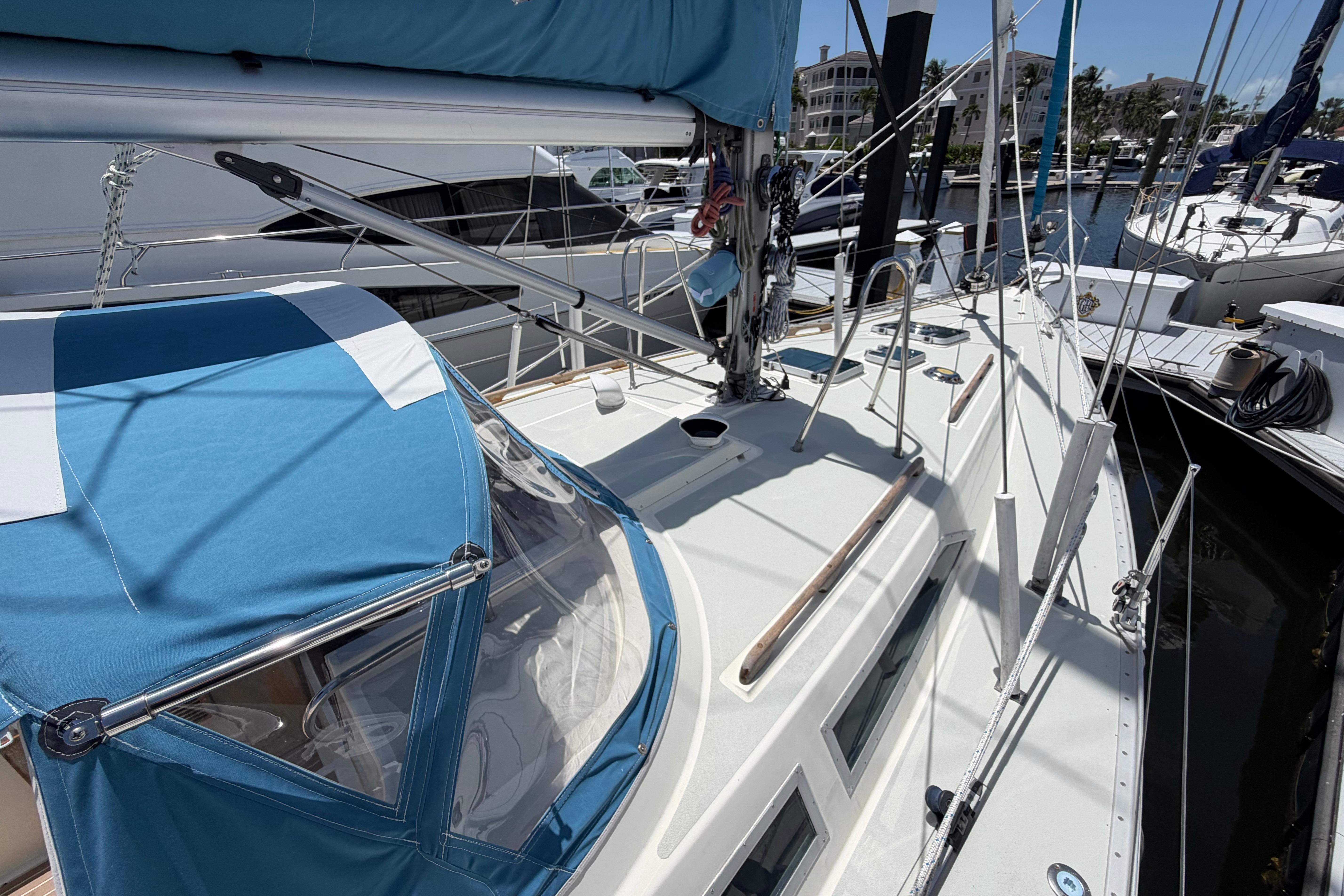 1987 Moody 376 sailboat with blue canopy docked at marina.