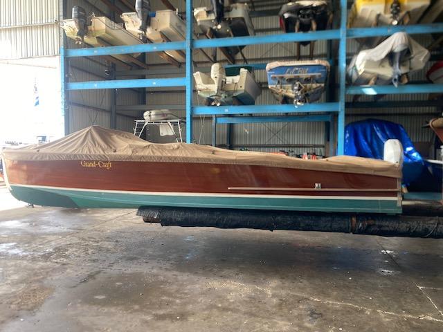 Grand Craft Classic Runabout 2000 in storage, covered, with other boats in the background.