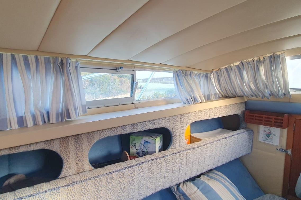Interior of 1989 Fairey Spearfish MKIII boat with striped curtains and cozy seating.