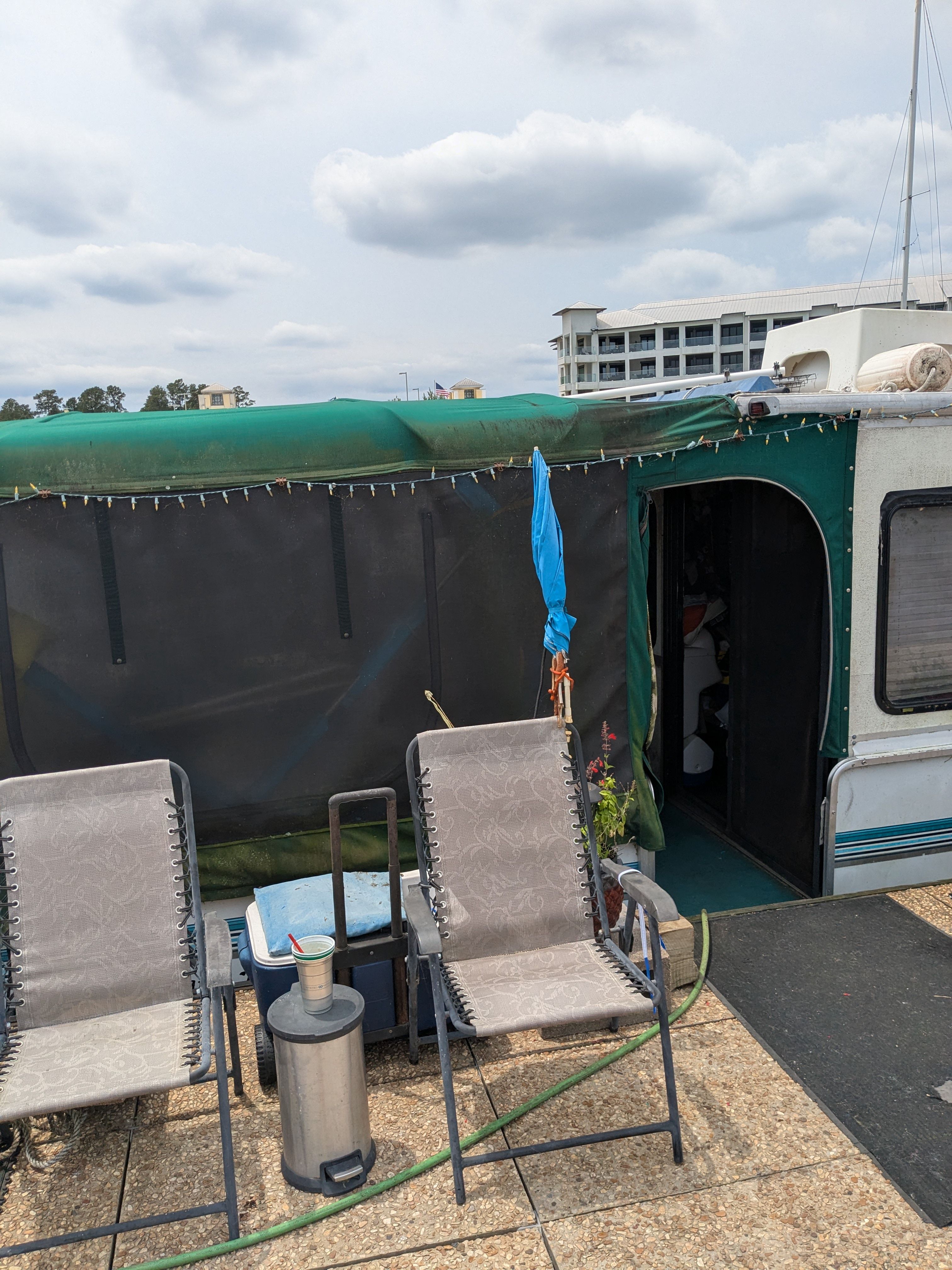 Two chairs on a boat with a green canopy and string lights.