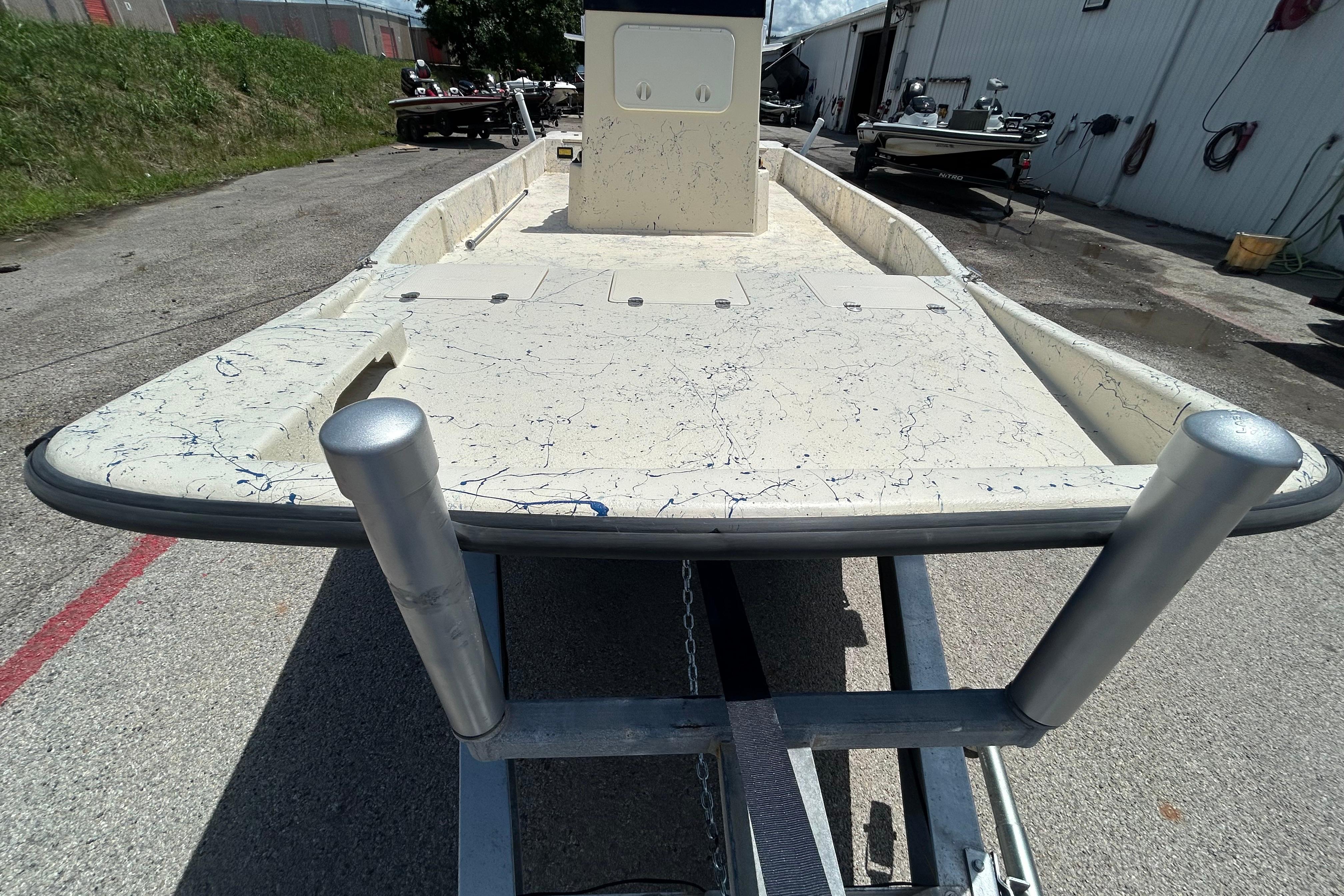 2007 Flats Cat 19 boat on trailer, parked outdoors near a warehouse.