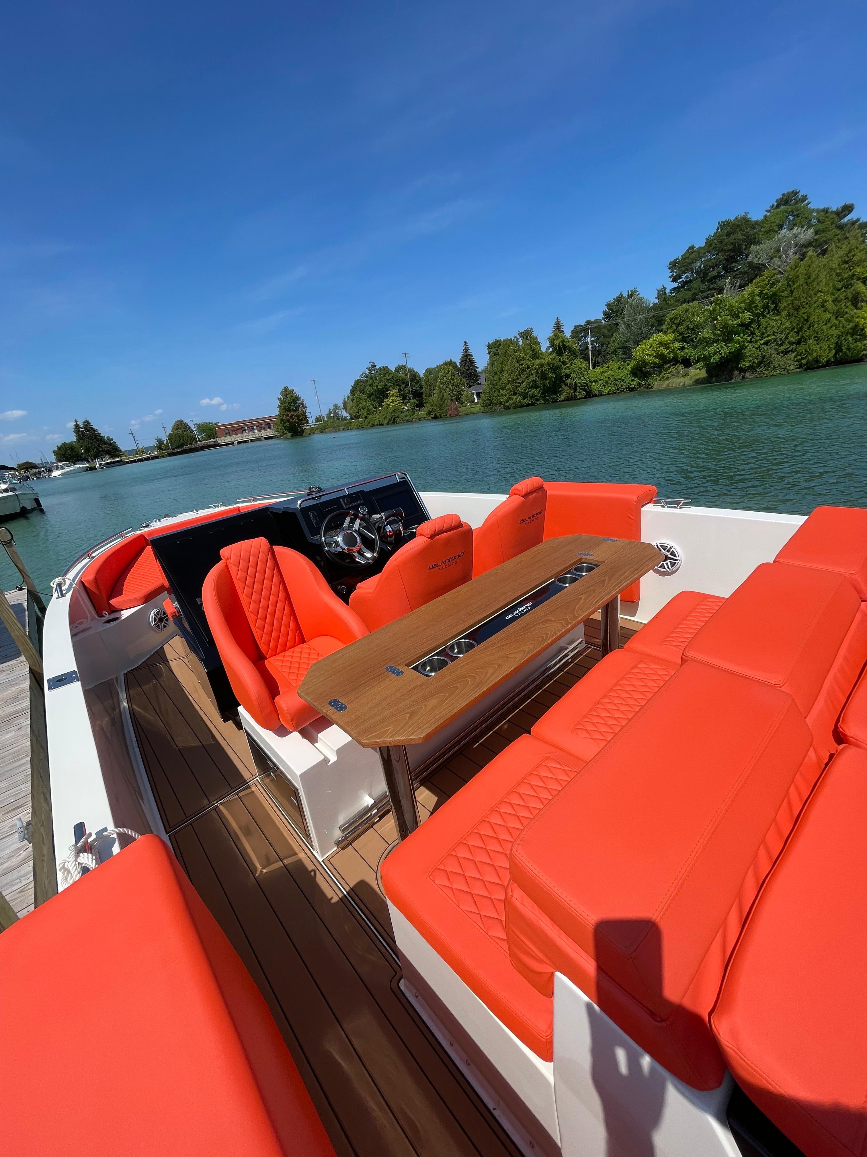 2020 De Antonio Yachts D 28 with vibrant orange seating on a serene waterway.