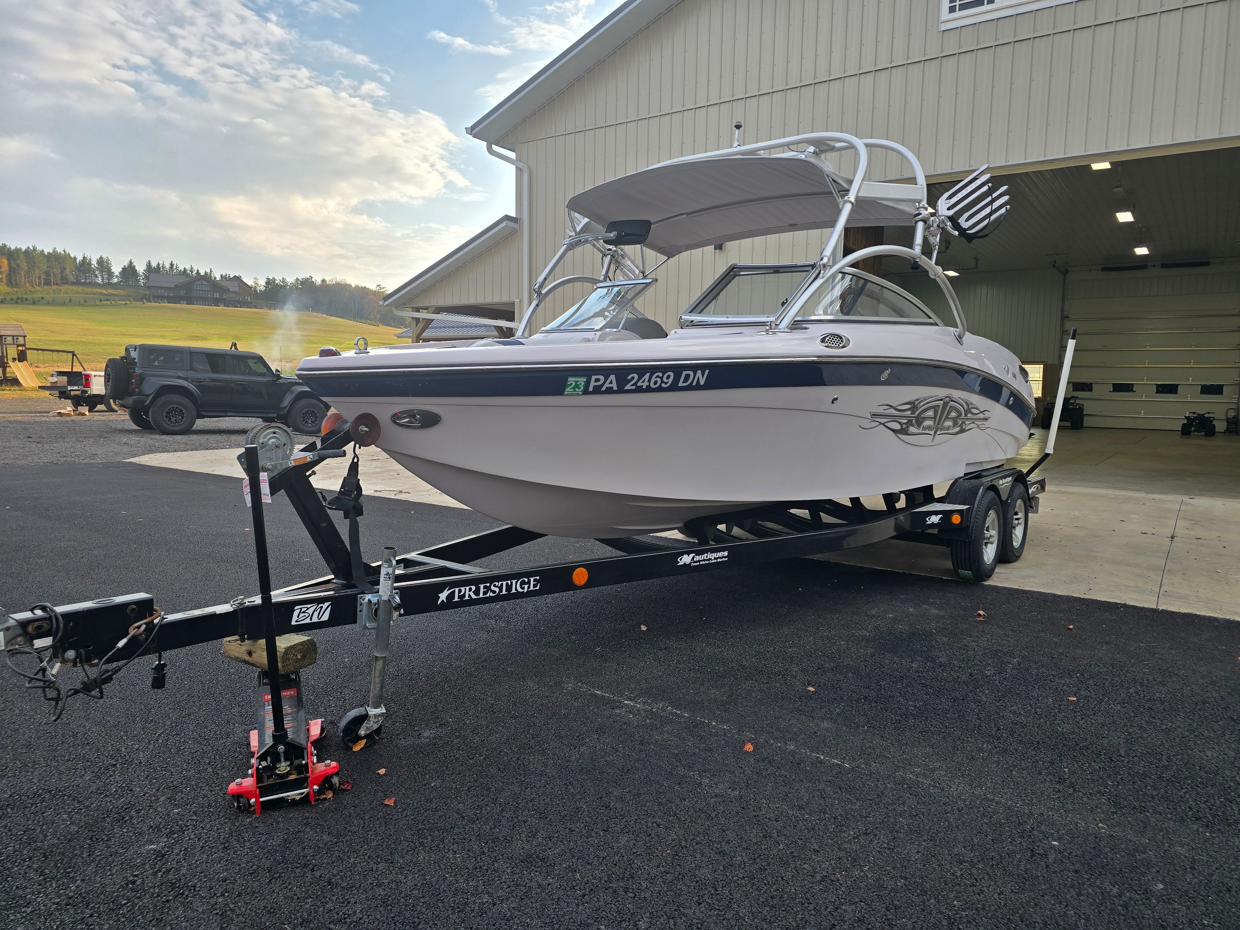 2006 Correct Craft 228 boat on trailer outside garage.