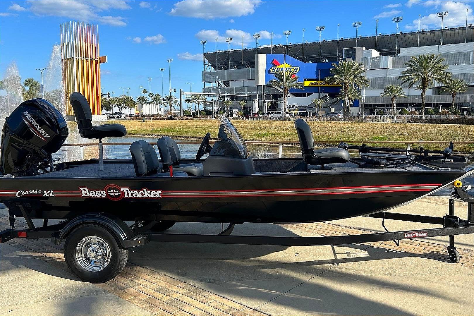 2026 Tracker Bass Tracker Classic XL boat parked near a stadium with palm trees.