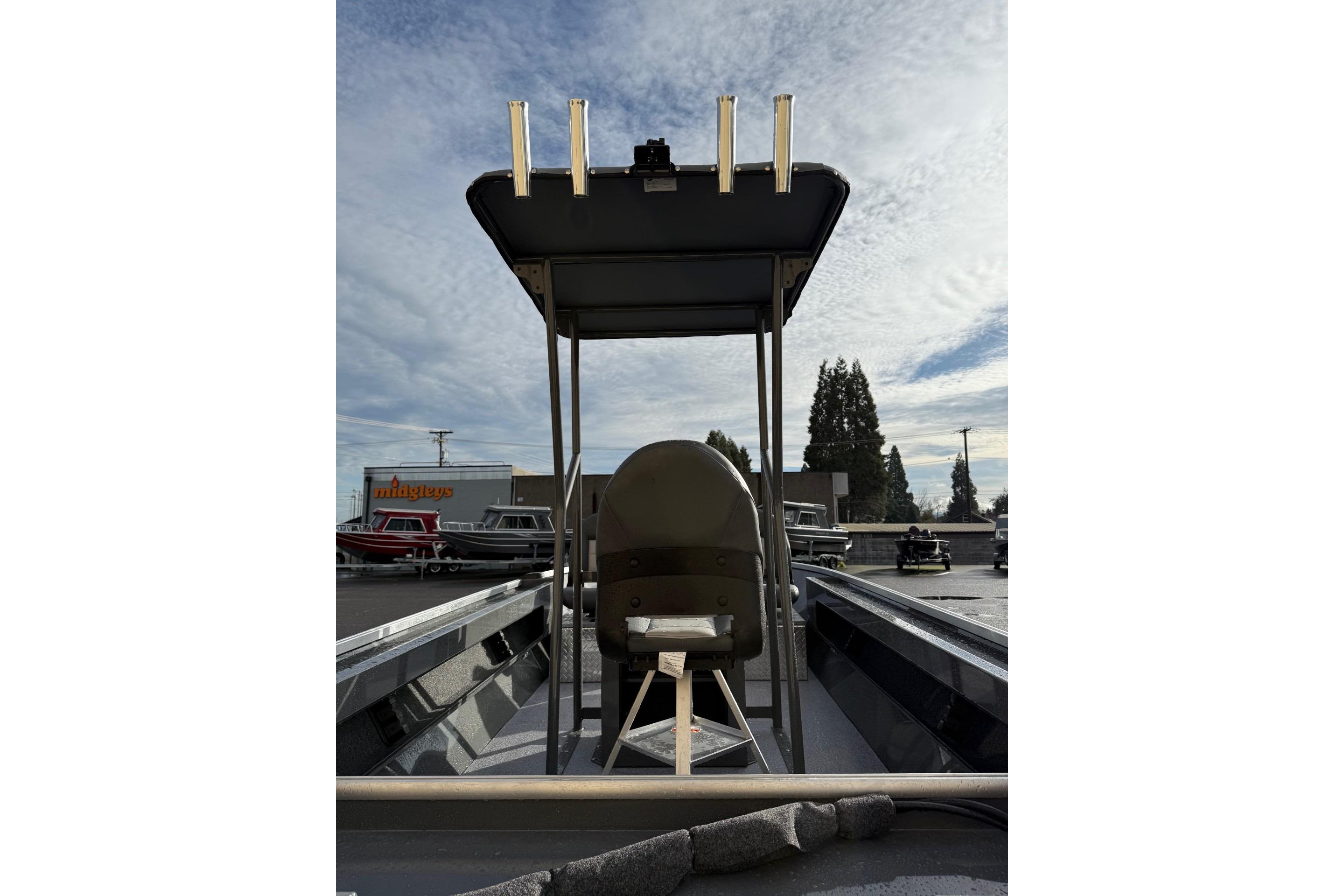 2026 Fish Rite Angler 18 boat with T-top and seating, parked outdoors under a cloudy sky.