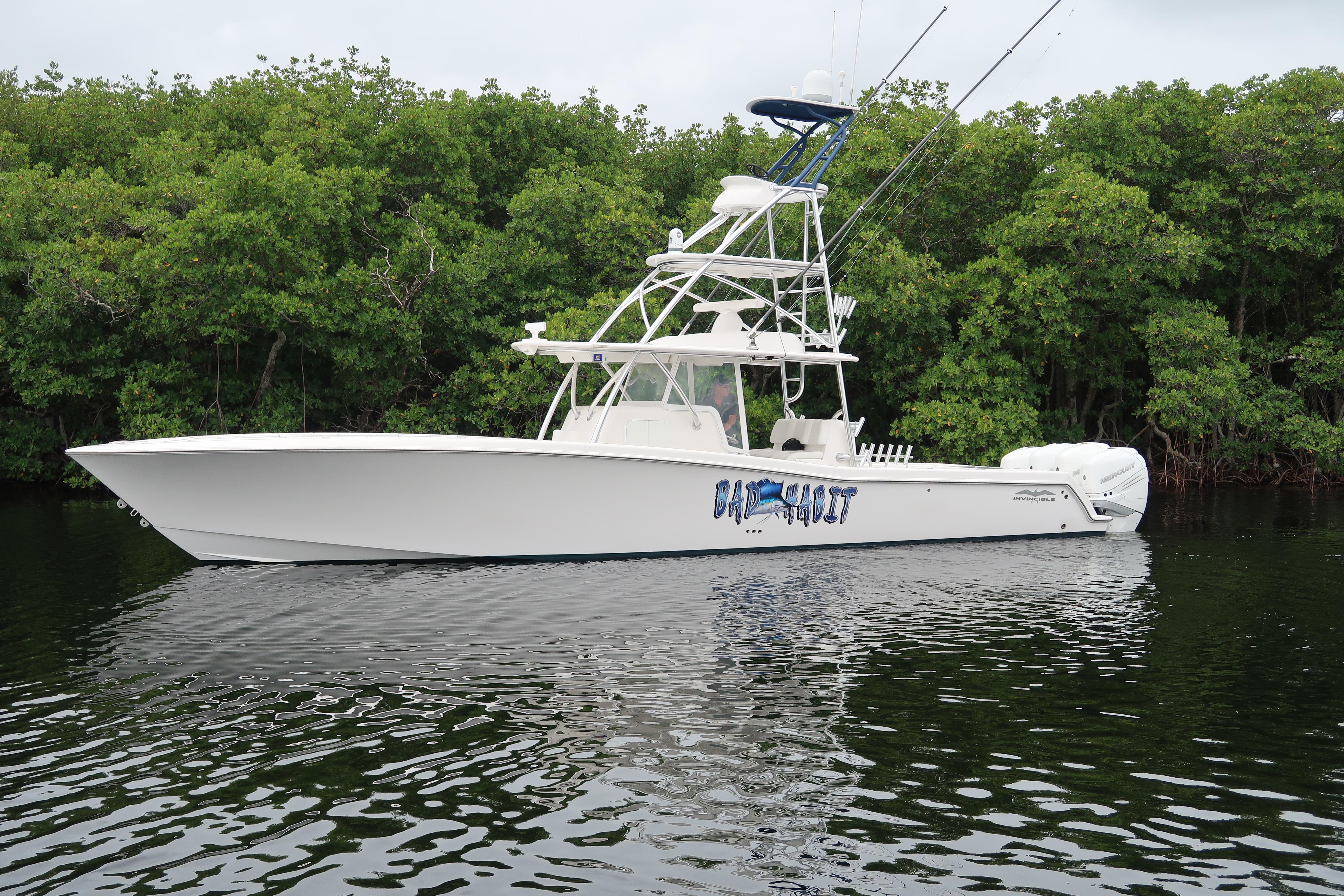 2016 Invincible 42 Open Fisherman boat on calm water near lush greenery.