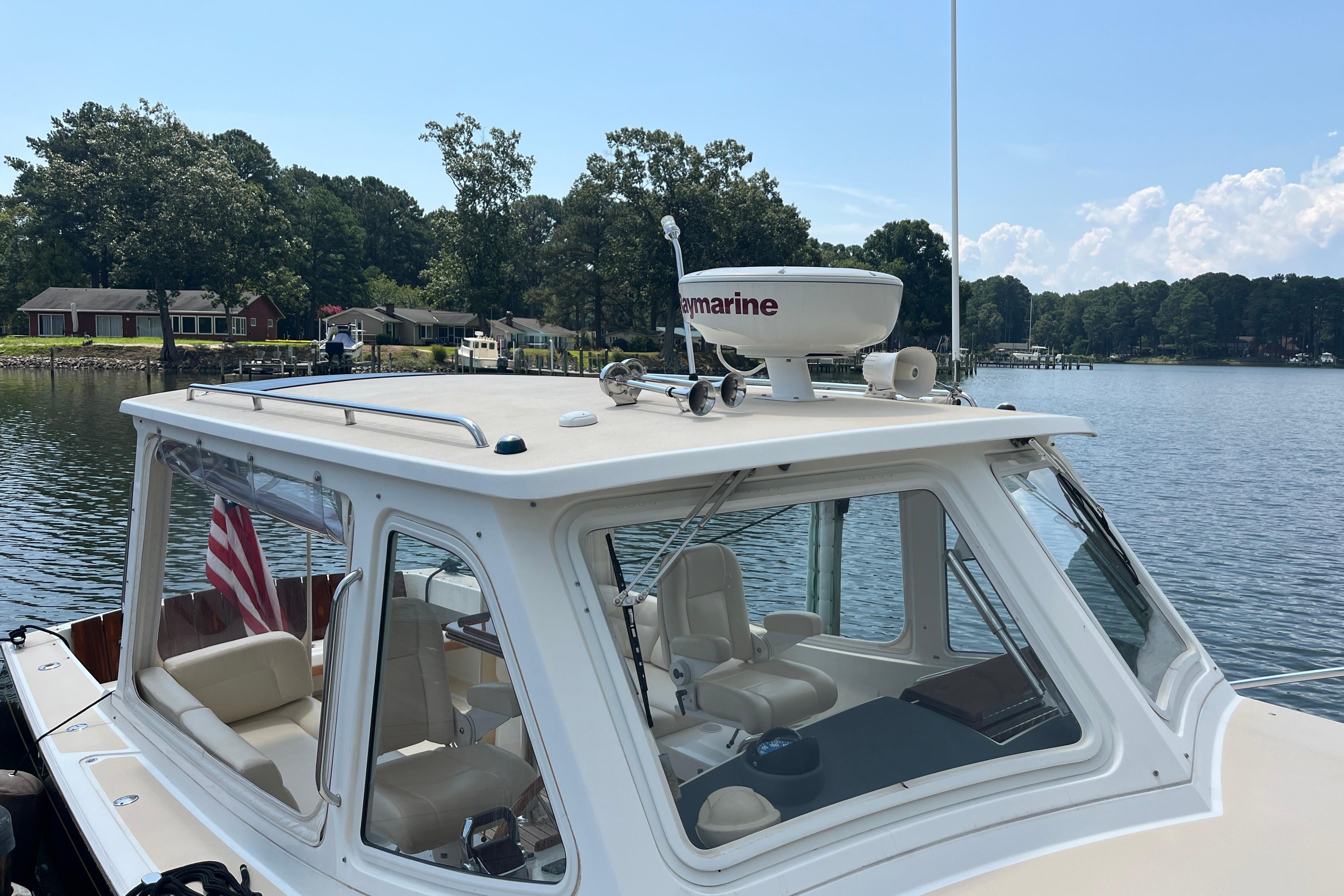 2006 MJM 34z boat docked on a serene lake with lush greenery.