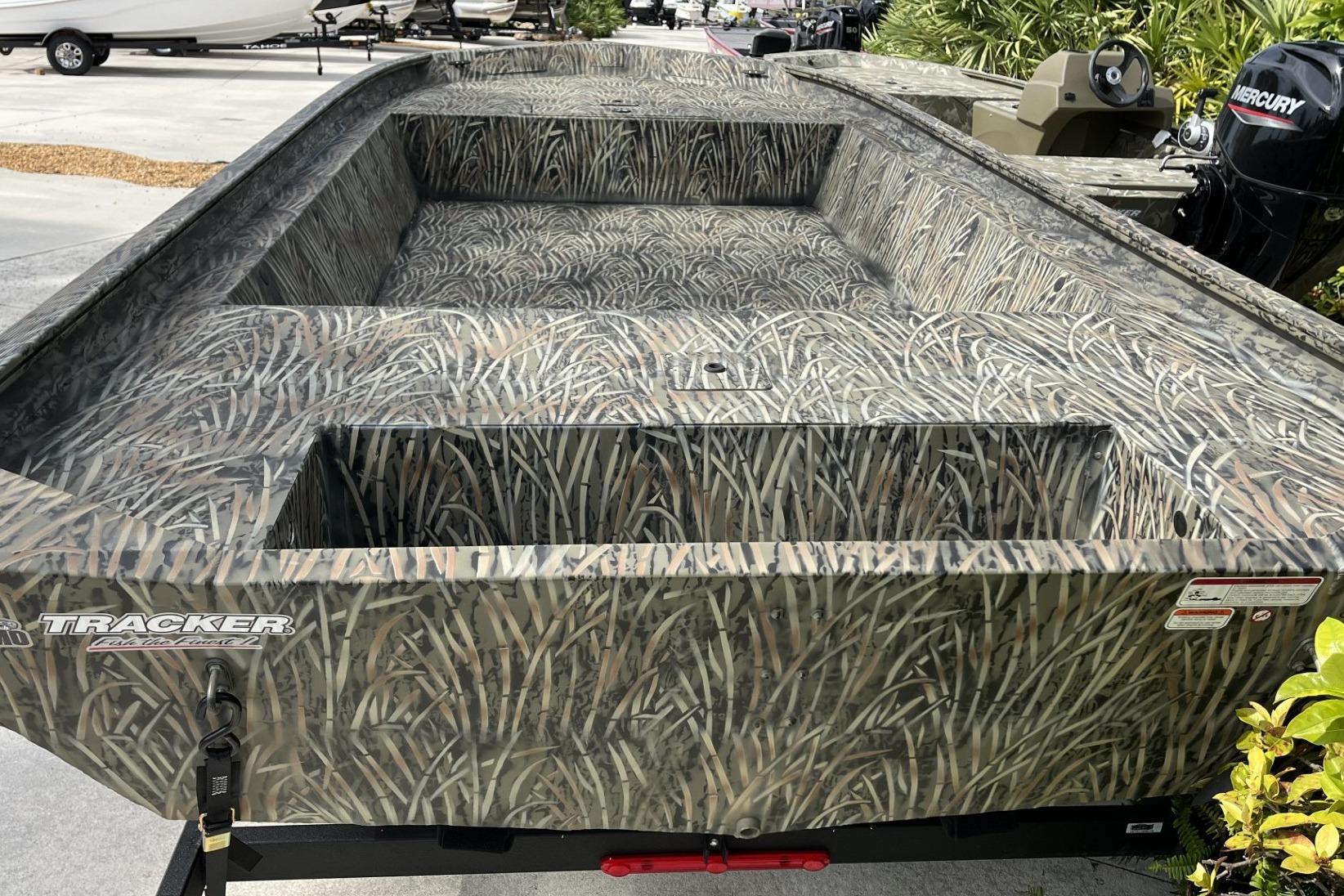 2025 Tracker Grizzly 1860 Utility boat with camouflage design, parked outdoors.