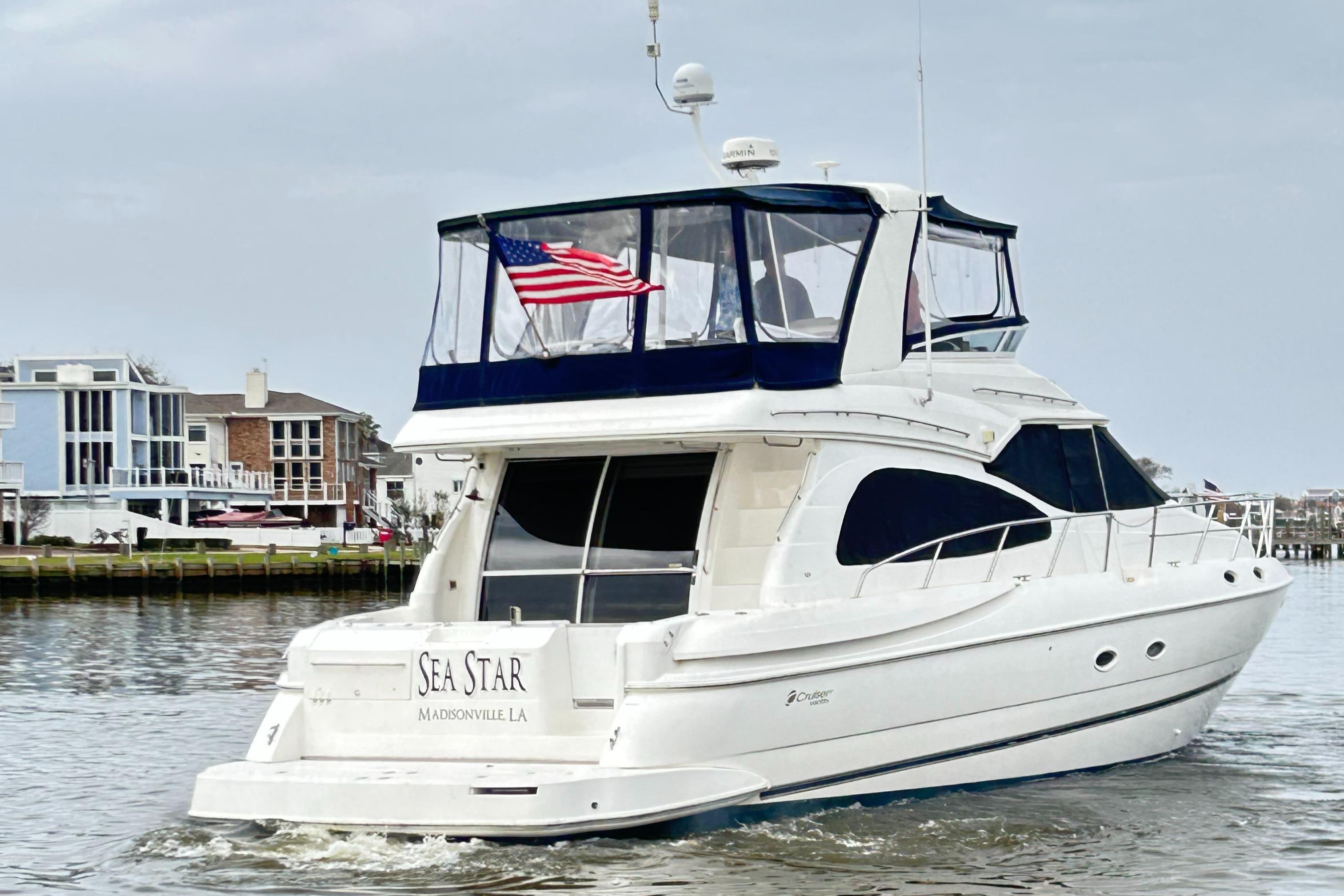 2004 Cruisers Yachts 5000 Sedan Sport on water, American flag, residential backdrop.
