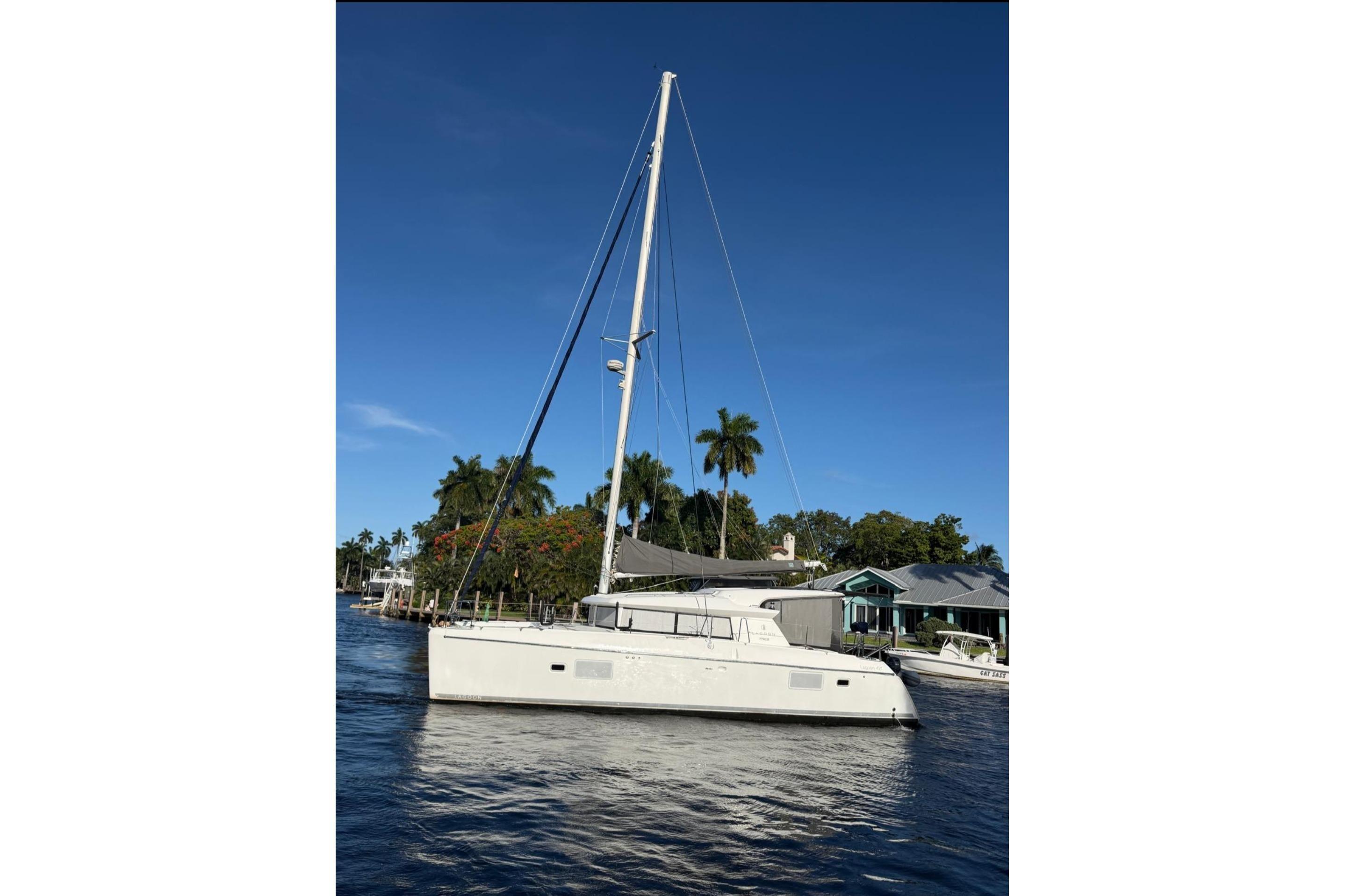 2010 Lagoon 421 catamaran sailing on a sunny day near palm trees.