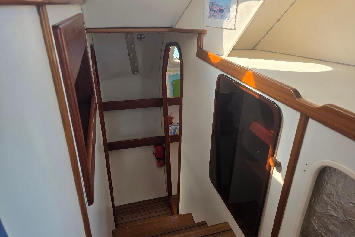 Interior view of 2003 Outremer 45 sailboat, featuring wooden stairs and cabin entrance.