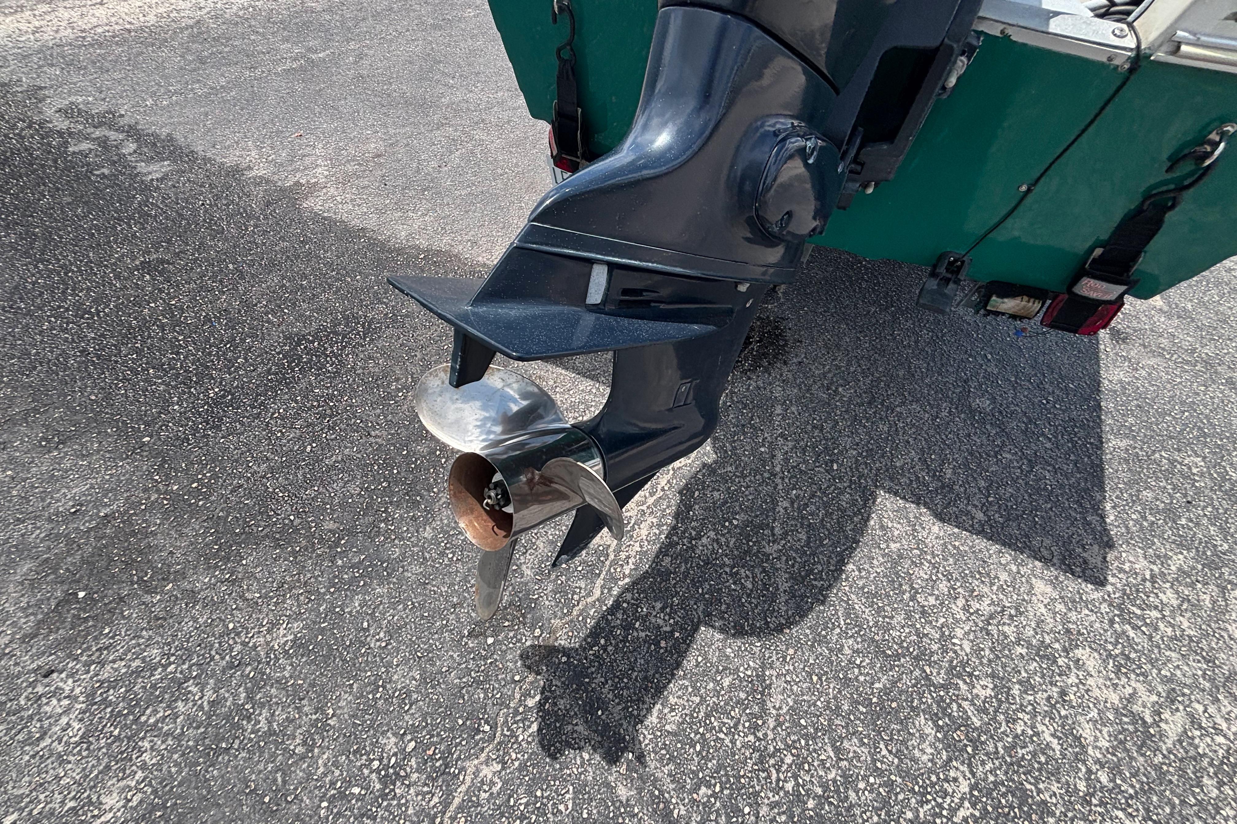 Outboard motor propeller of a 1966 Mohawk 15 boat on asphalt surface.