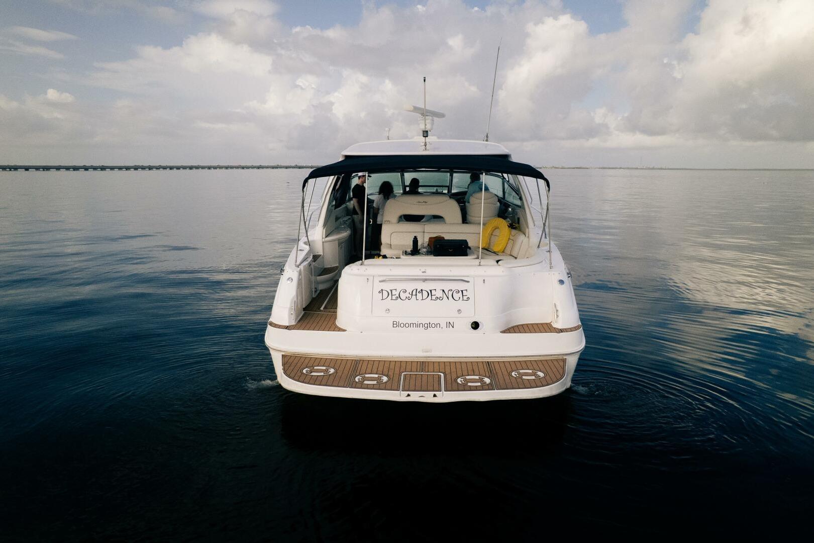 2003 Sea Ray Sundancer 460 yacht on calm water, rear view, under cloudy sky.