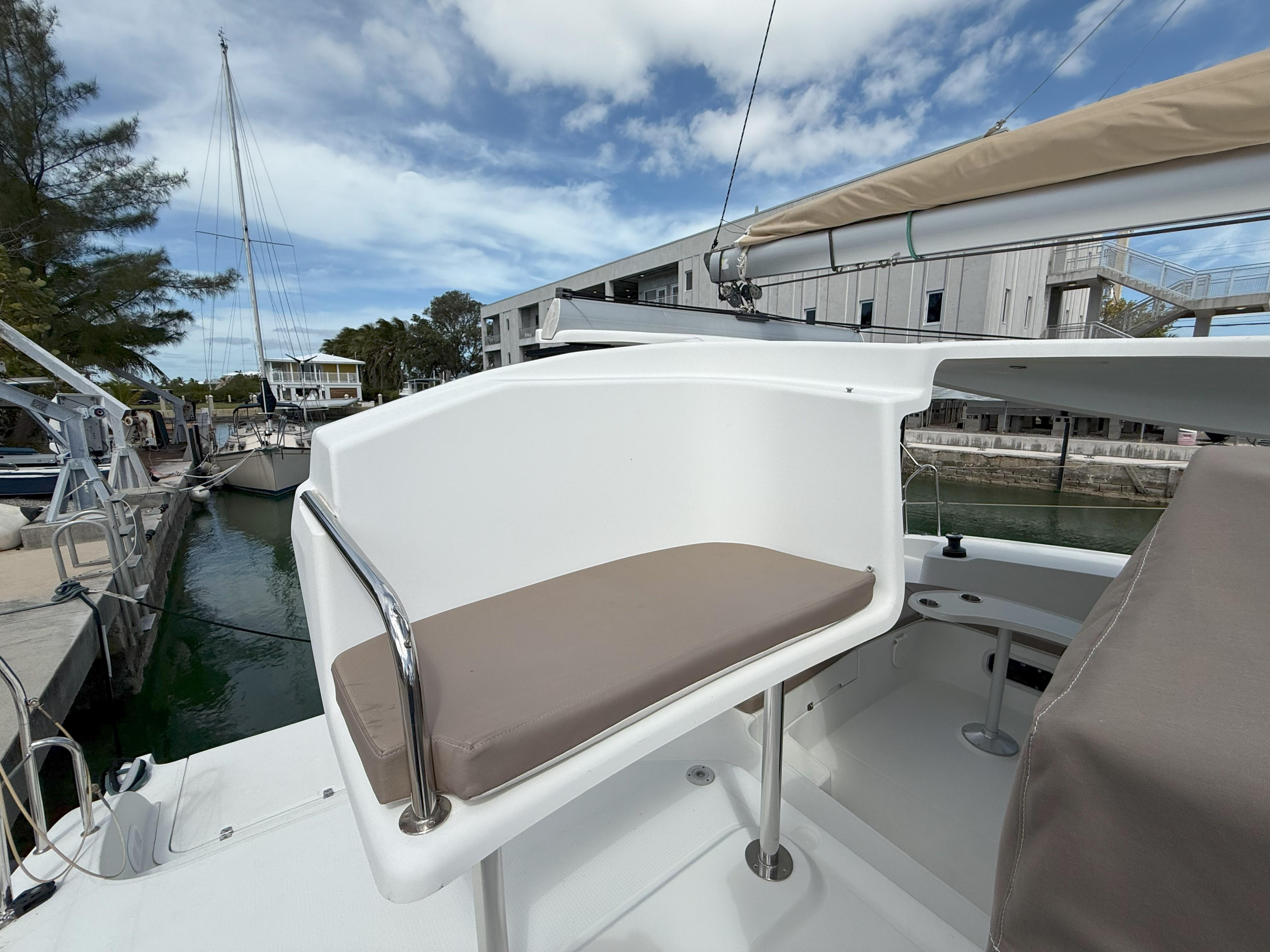 2014 Fountaine Pajot Mahe 36 Evolution yacht helm station with cushioned seat, docked at marina.