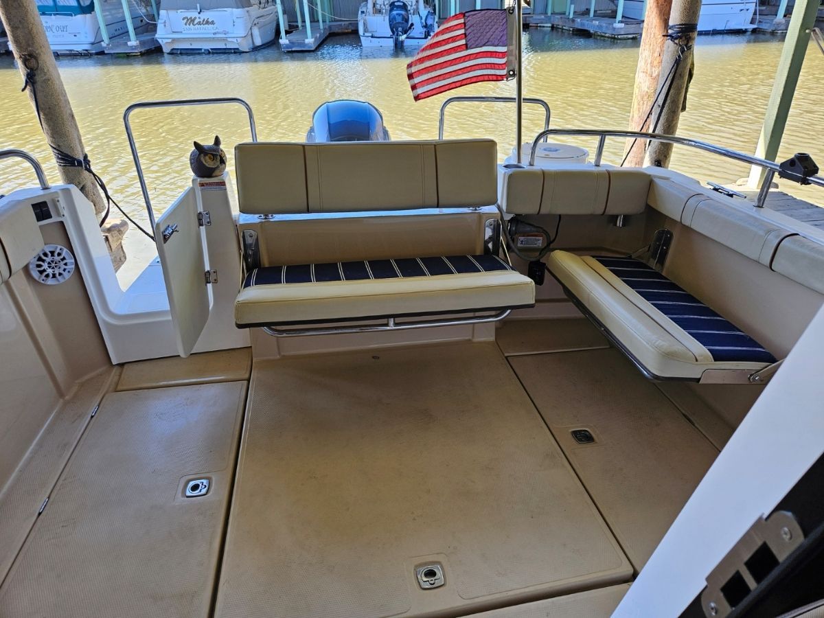 The image shows the cockpit of a 2020 Ranger Tugs R-23 with beige seating and an American flag.