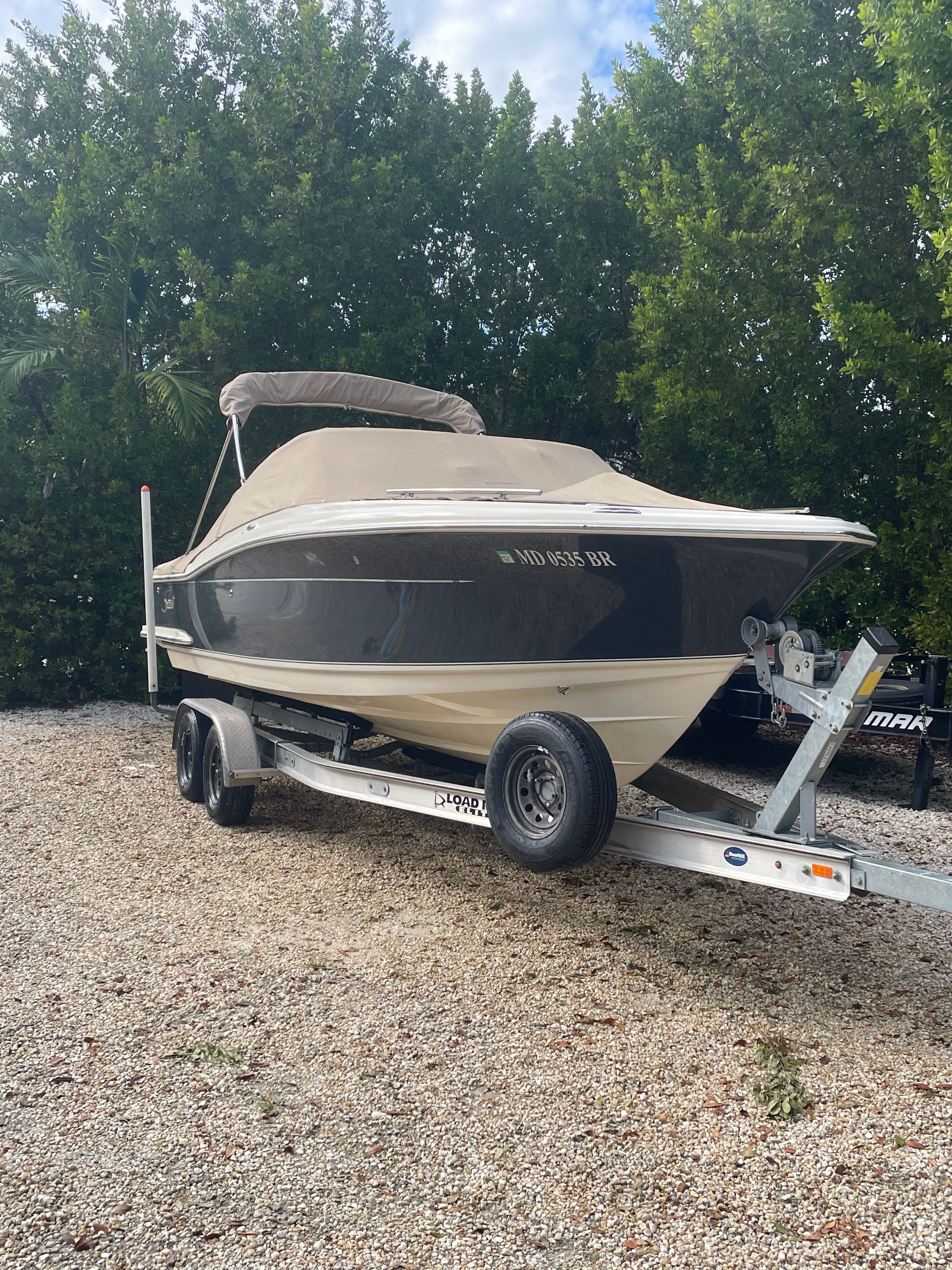 A 2020 Scout 235 Dorado boat on a trailer, surrounded by trees.