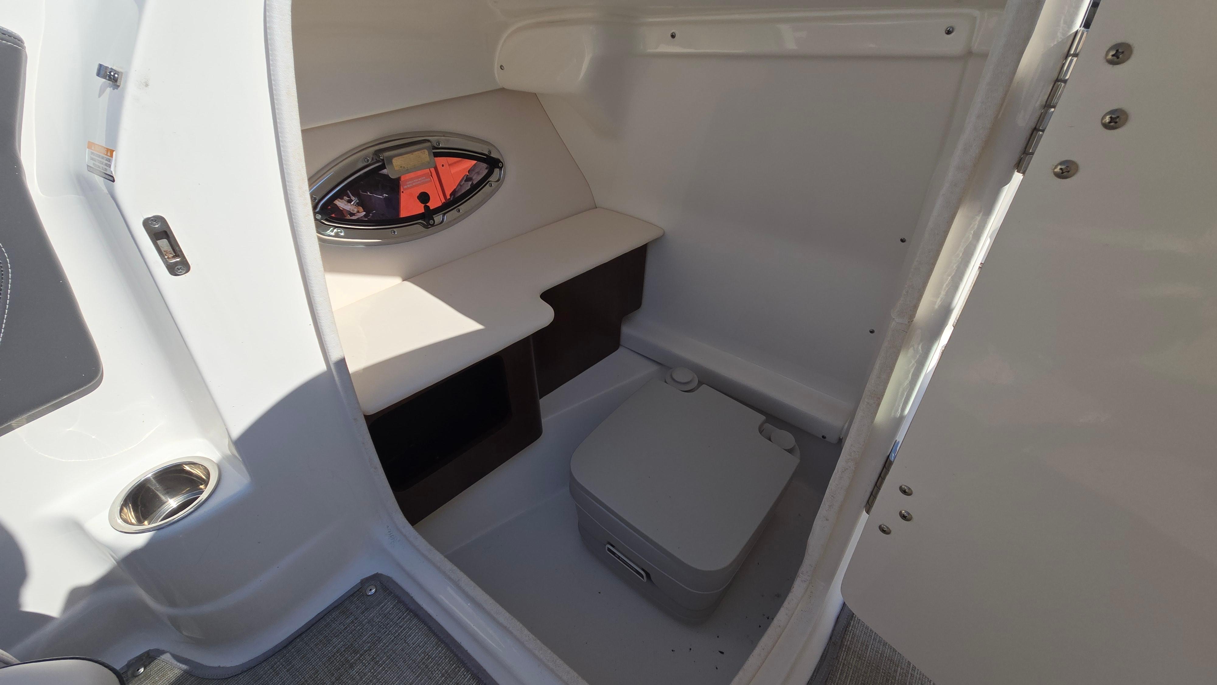 2018 Chaparral 224 Sunesta boat interior with compact restroom and porthole window.