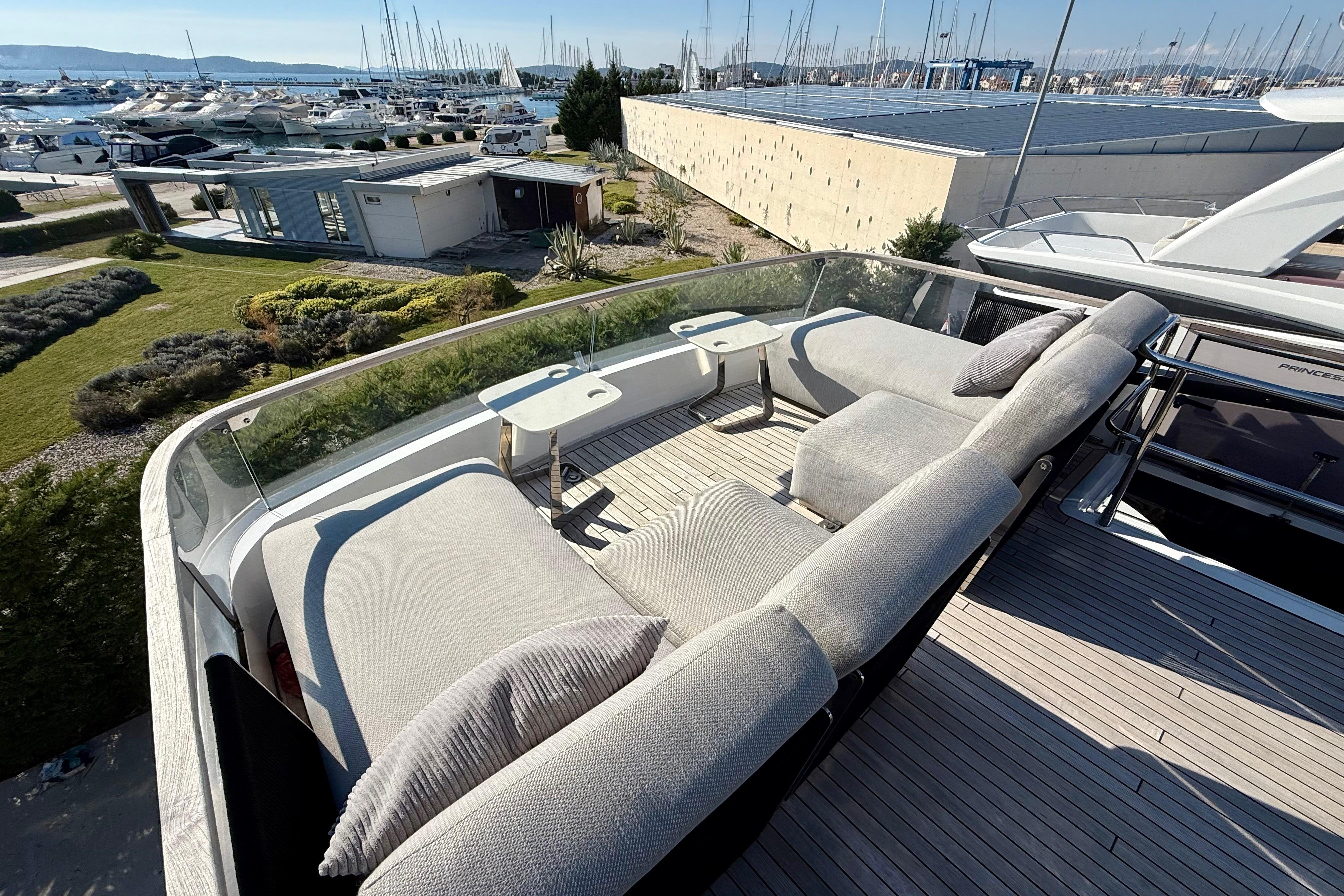 Luxurious 2022 Fairline Squadron 68 yacht with spacious outdoor seating and scenic marina view.