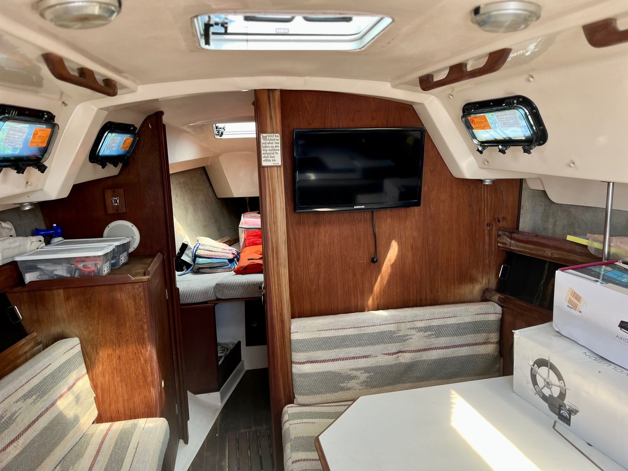 Interior of a 1985 Hunter 30 sailboat with cozy seating areas and a television.