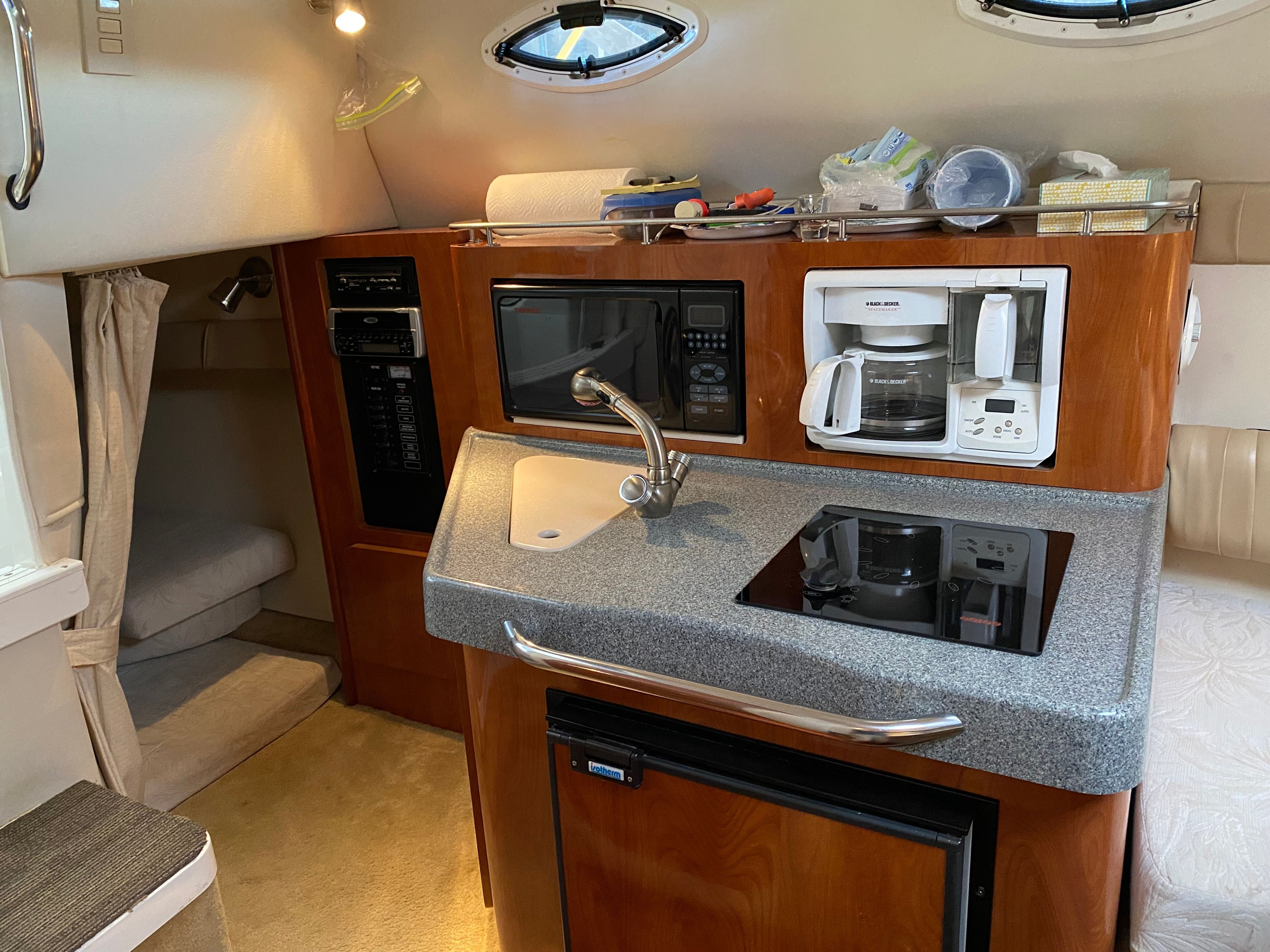 The galley of a 2005 Larson Cabrio 240 with sink, stove, microwave, and coffee maker.