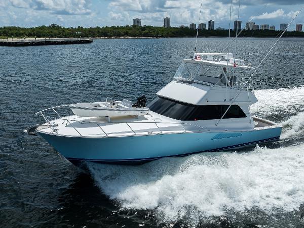 Viking 50 Convertible 2000 yacht cruising on open water with city skyline in background.