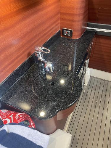 2017 Mystic Powerboats M4200 interior sink with black countertop and wooden paneling.