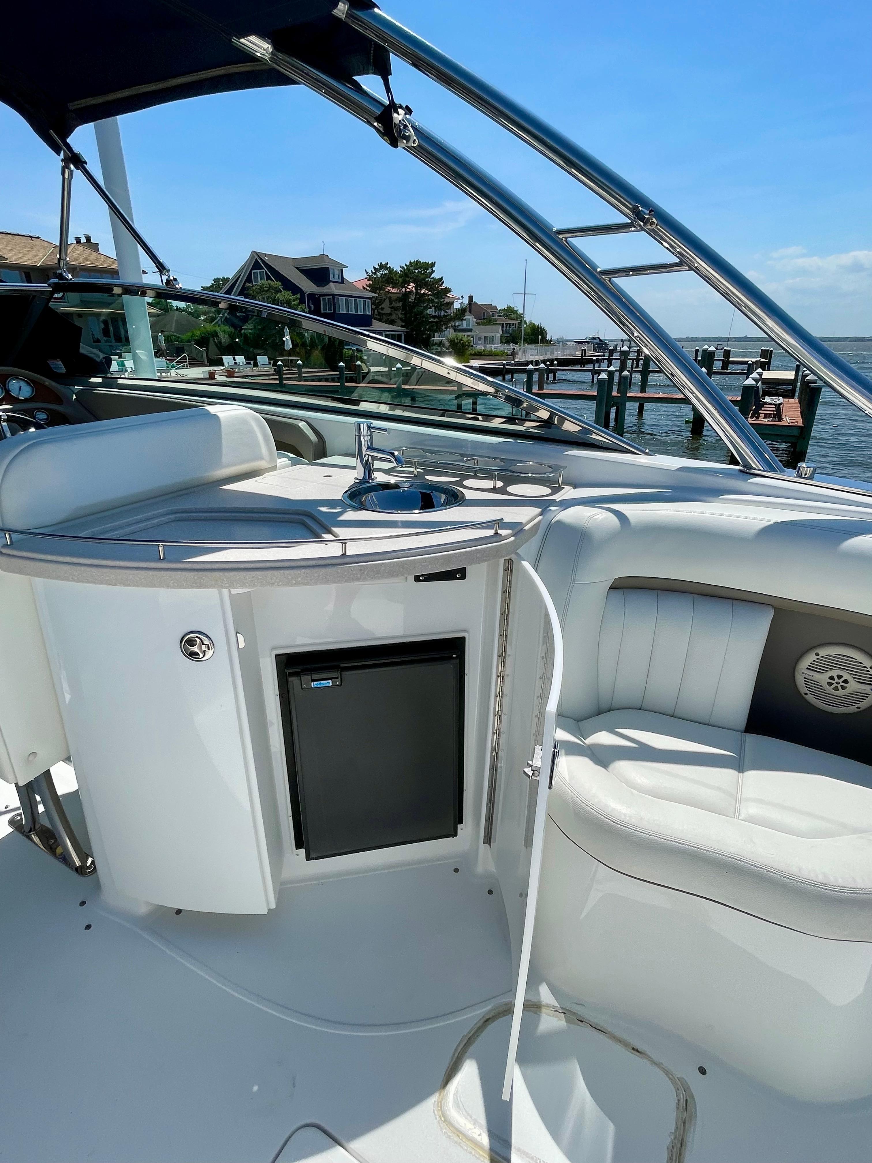 2006 Cobalt 323 boat interior with seating, mini fridge, and sink, docked by waterfront homes.