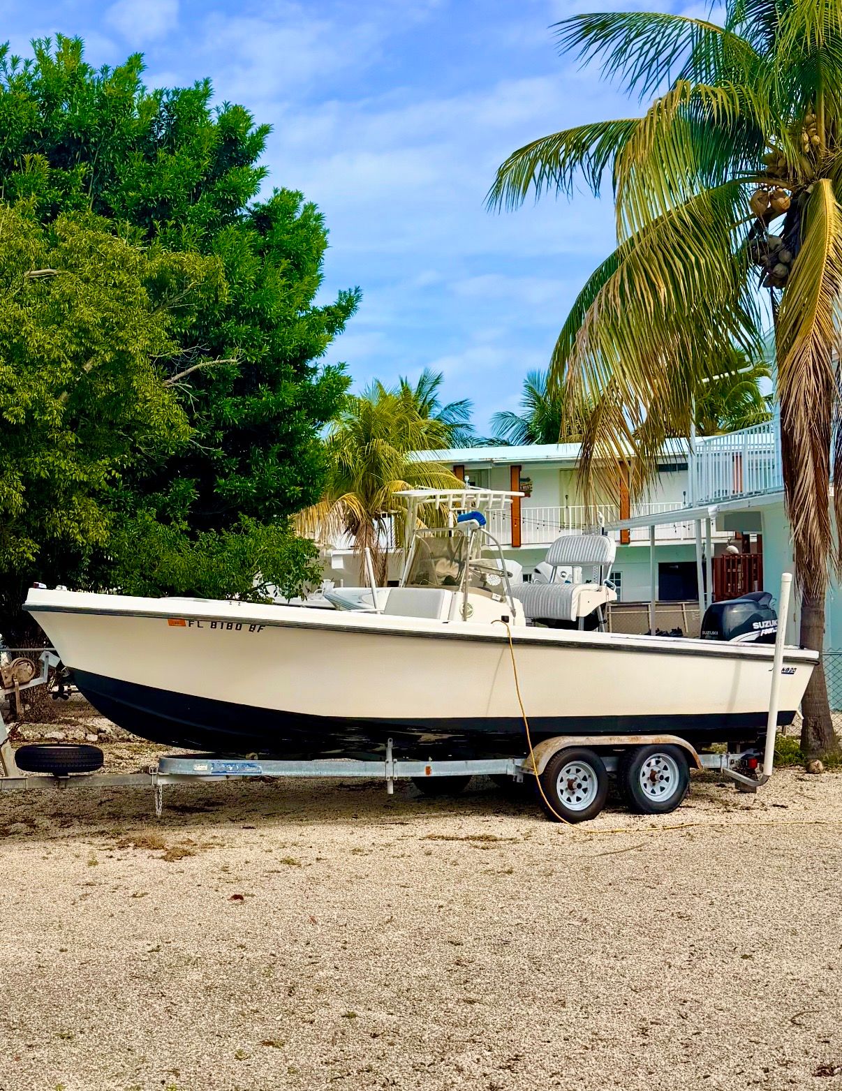1970 Mako 20 boat on trailer under palm trees.