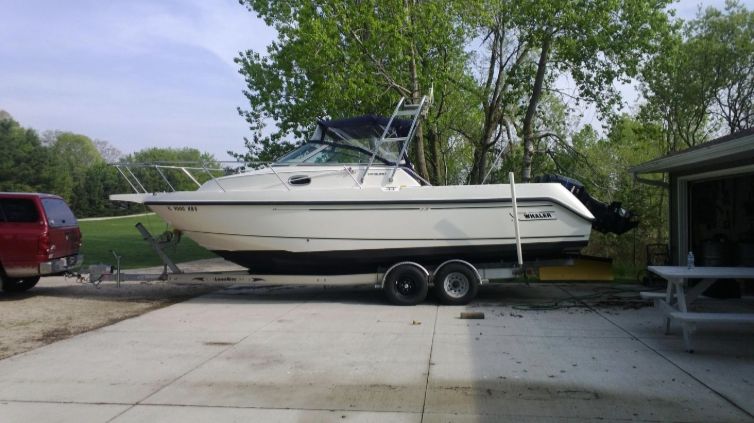 A 2001 Boston Whaler 26 Conquest on a trailer in a driveway.