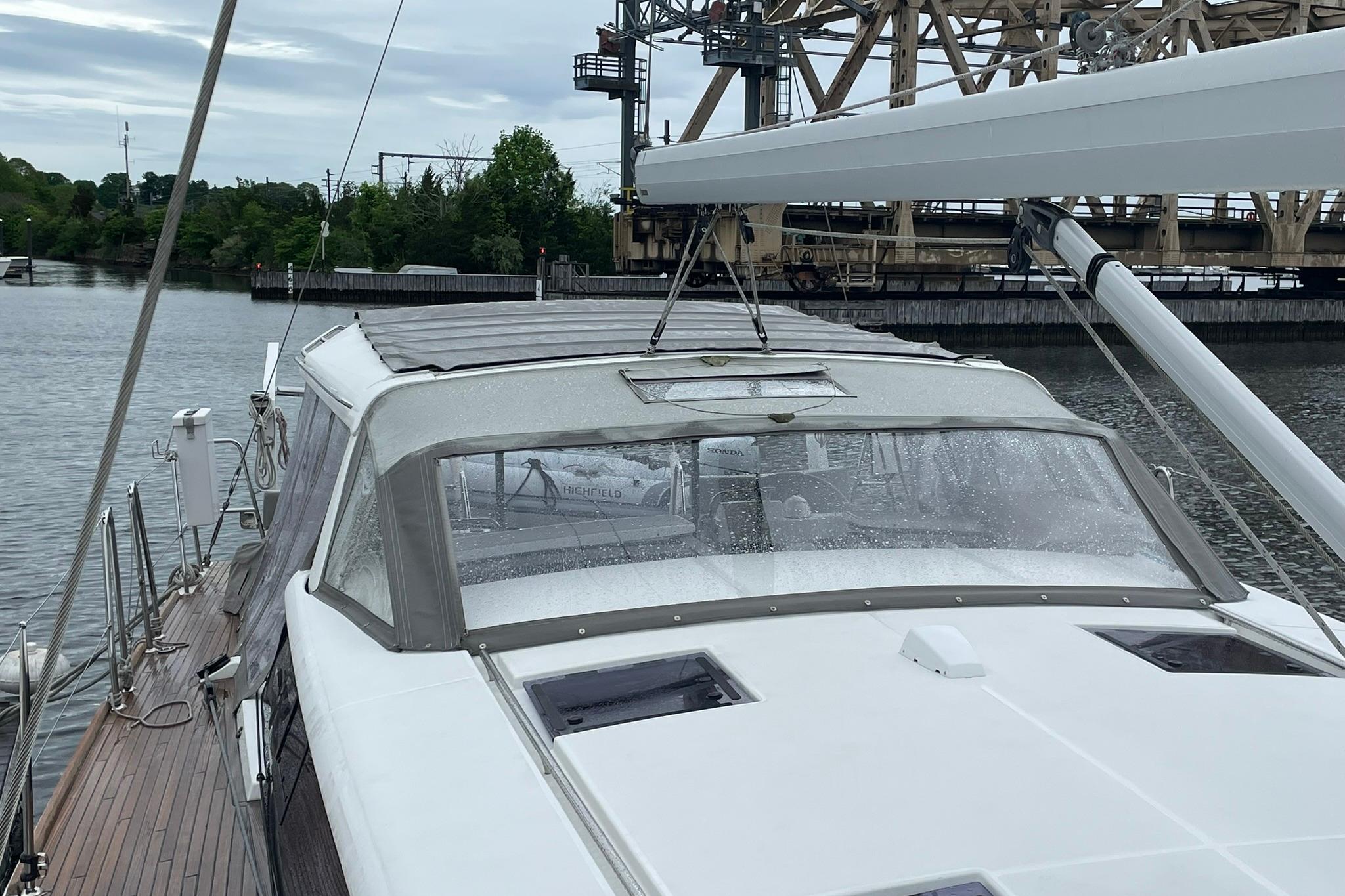 2017 Beneteau Sense 57 yacht docked near an industrial bridge on a cloudy day.