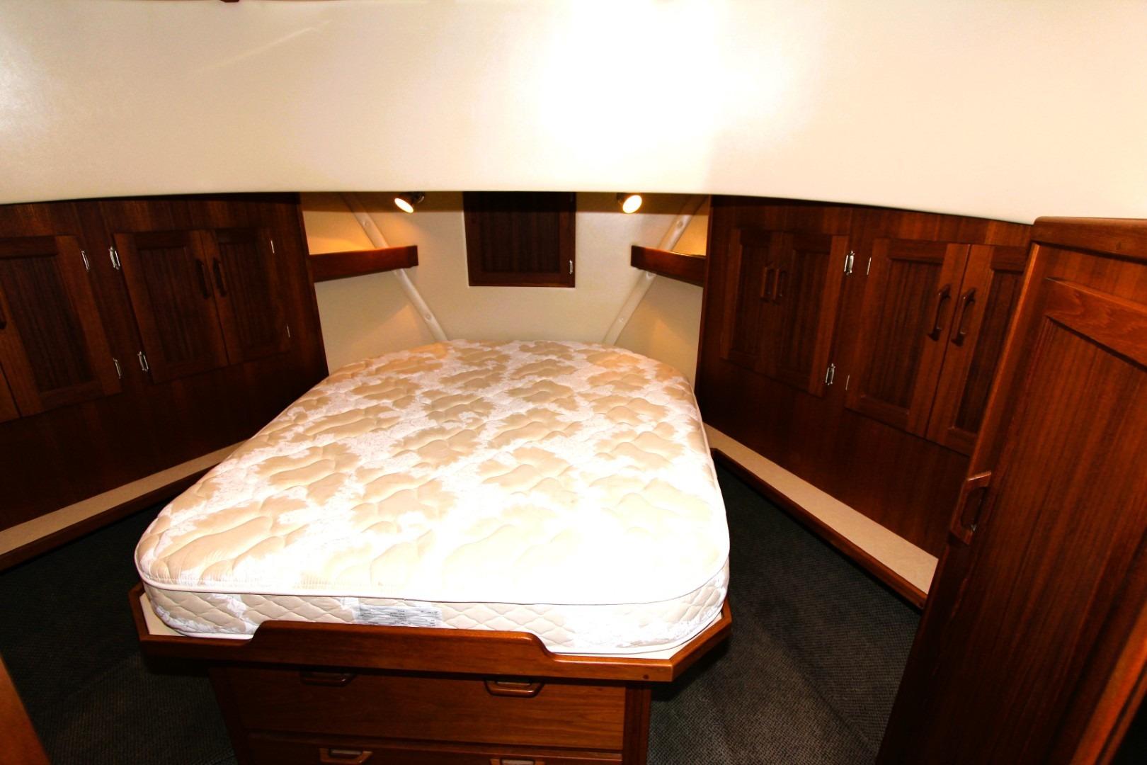 Cozy cabin interior of 2002 Nordic Tug 37 with wooden cabinetry and a comfortable bed.