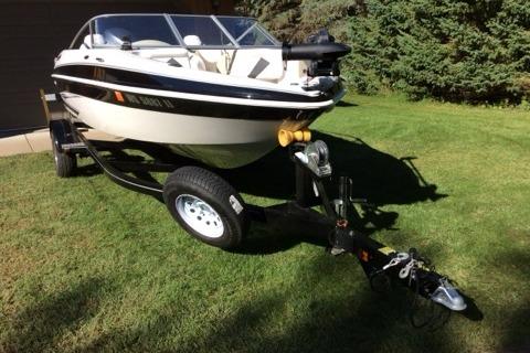 2012 Glastron GT180 boat on trailer, parked on grass, ready for transport.
