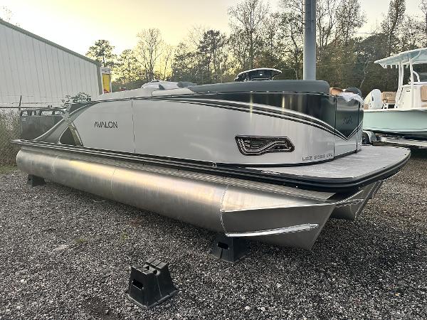 2025 Avalon LSZ Versatile Rear Lounger pontoon boat on gravel lot, side view.