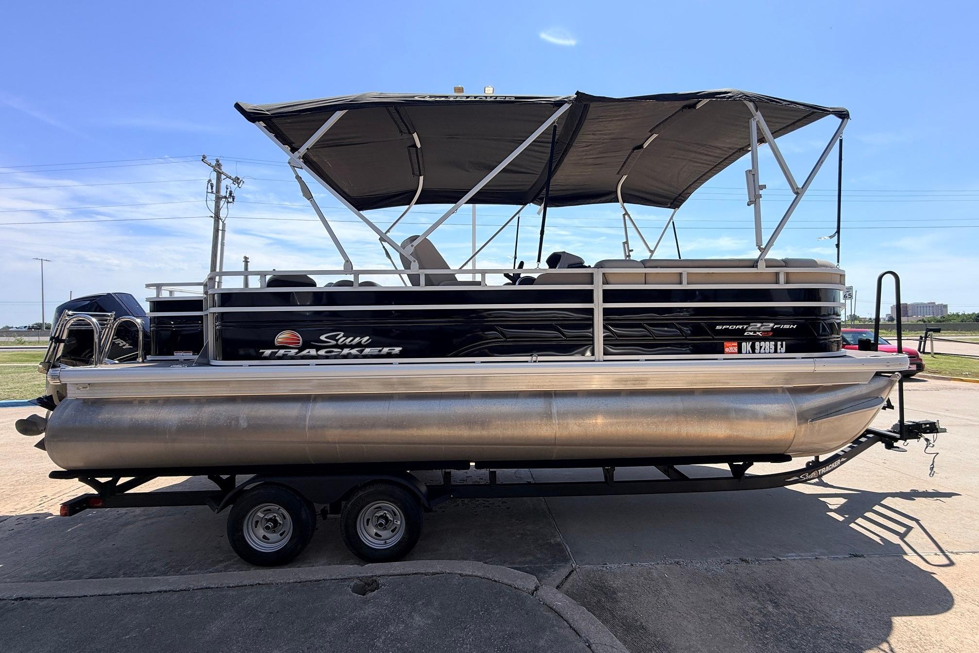 2024 Sun Tracker SportFish 22 XP3 pontoon boat on trailer, side view.