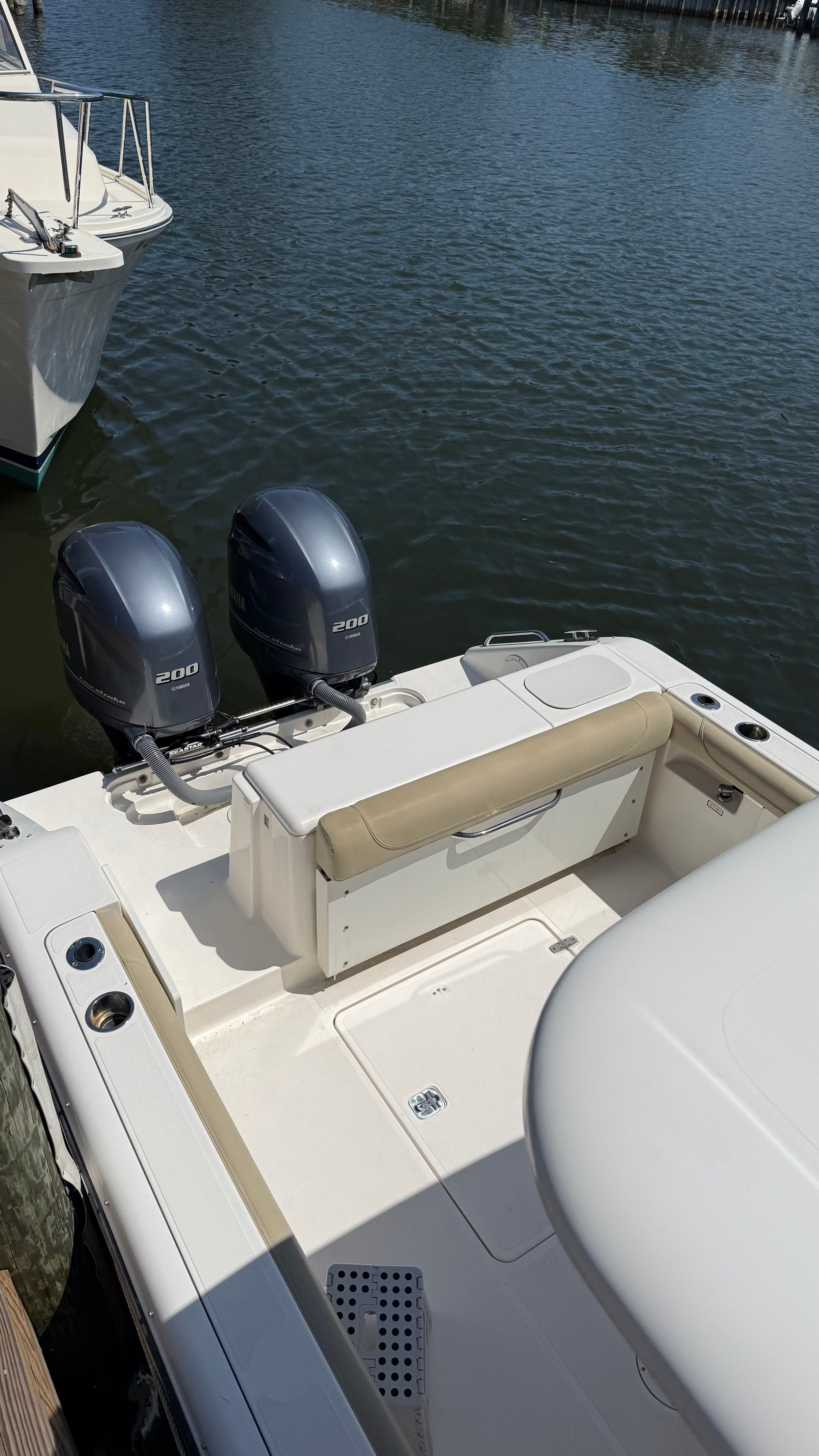 A 2016 Pursuit DC 265 Dual Console docked. It features two outboard engines.