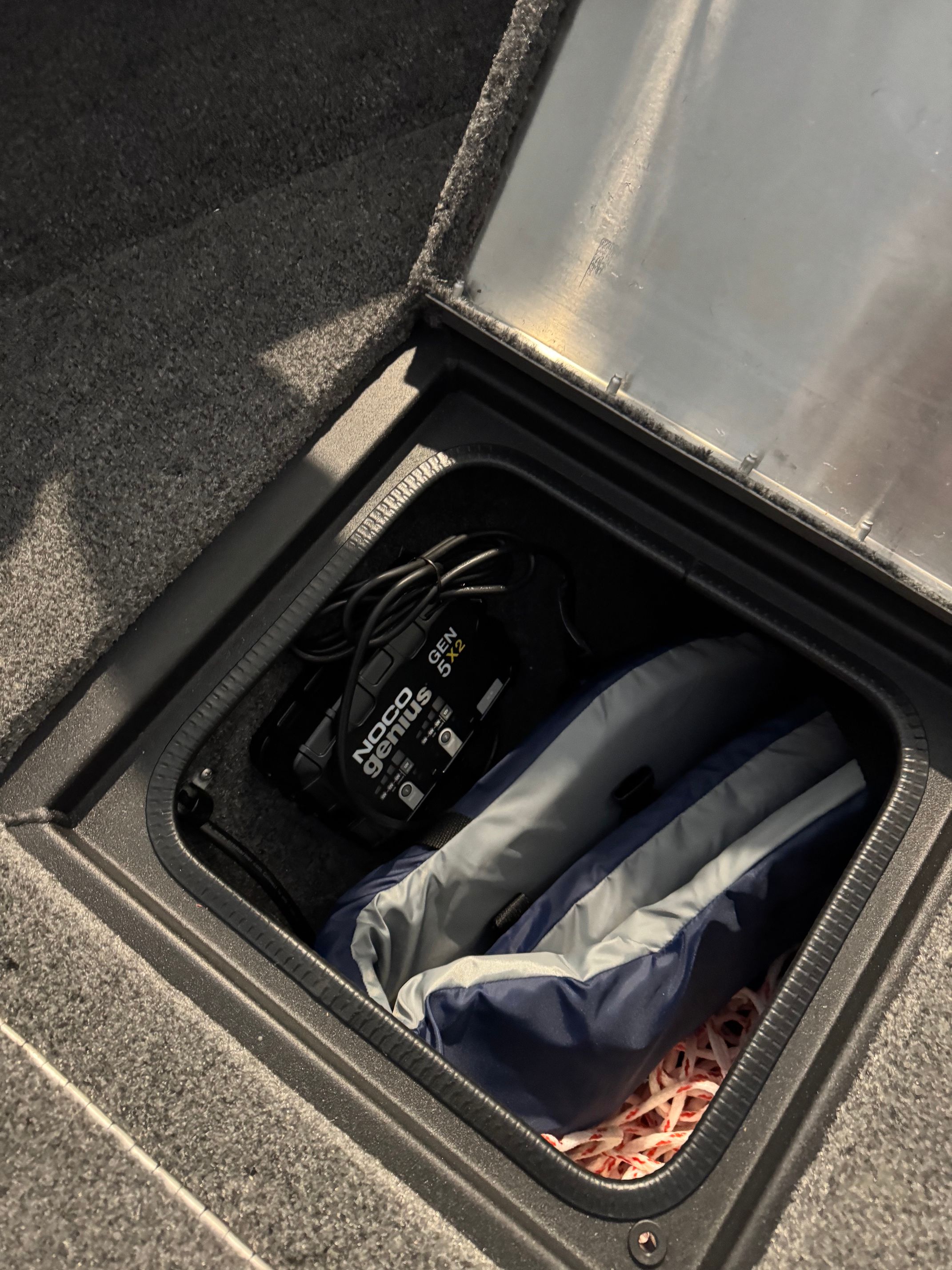 An open storage compartment with a battery and a life jacket inside.