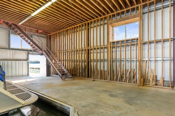 Spacious 1985 Custom Larson Boathouse interior with wooden beams and staircase.