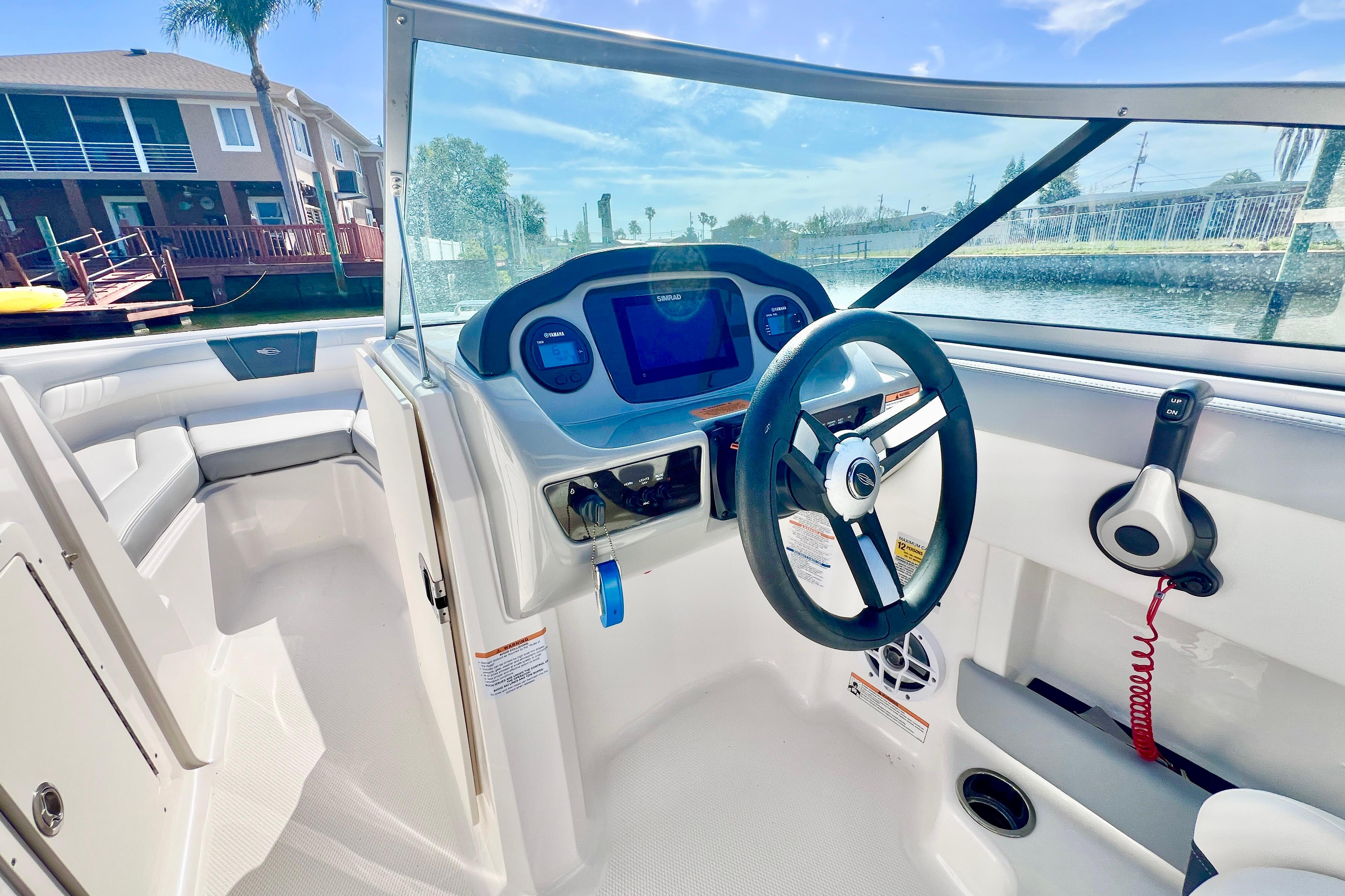 2023 Chaparral 21 SSi OB boat interior with steering wheel and dashboard, dockside view.