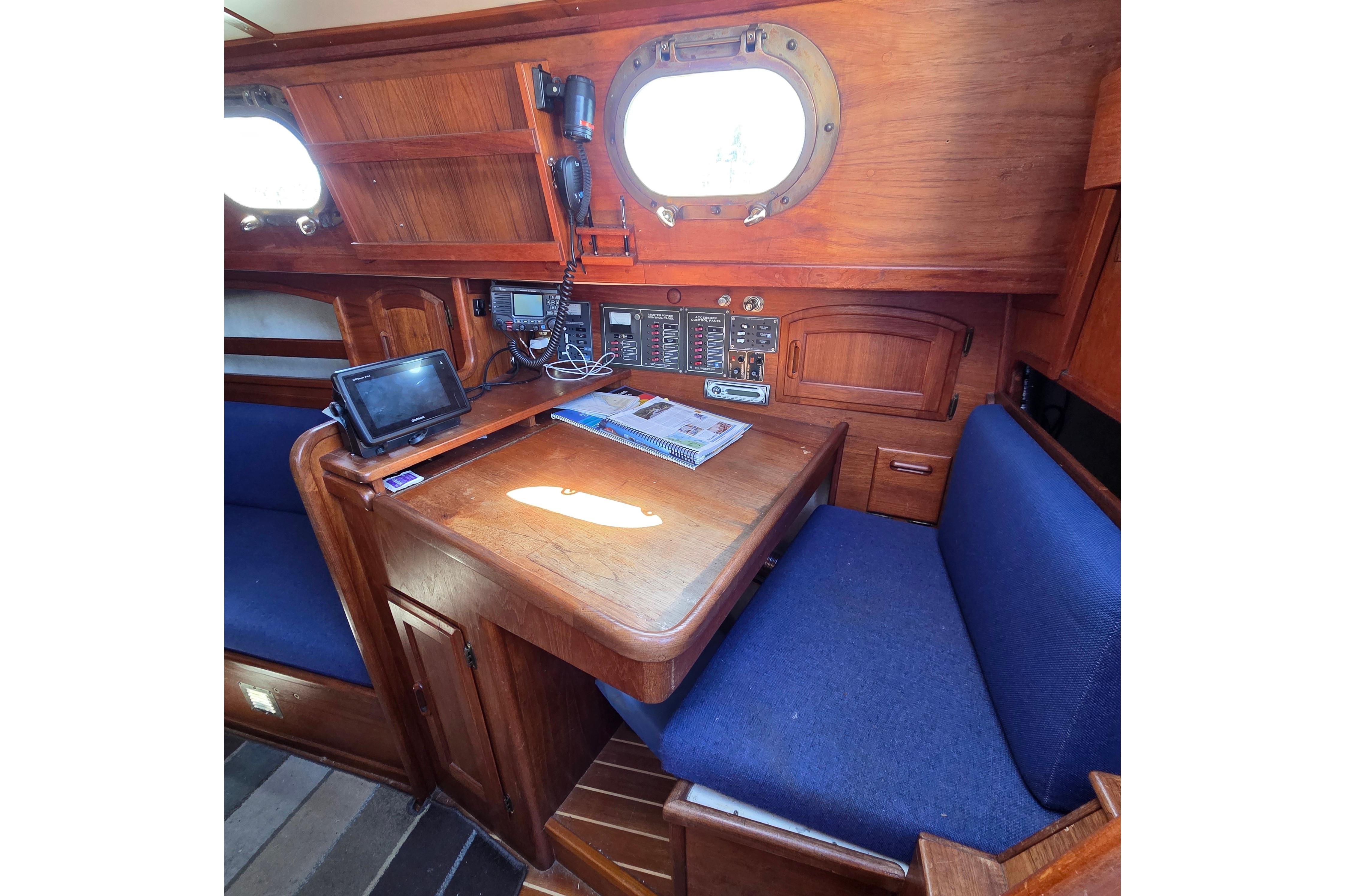 Interior of 1983 Pacific Seacraft 34 sailboat with navigation station and blue seating.