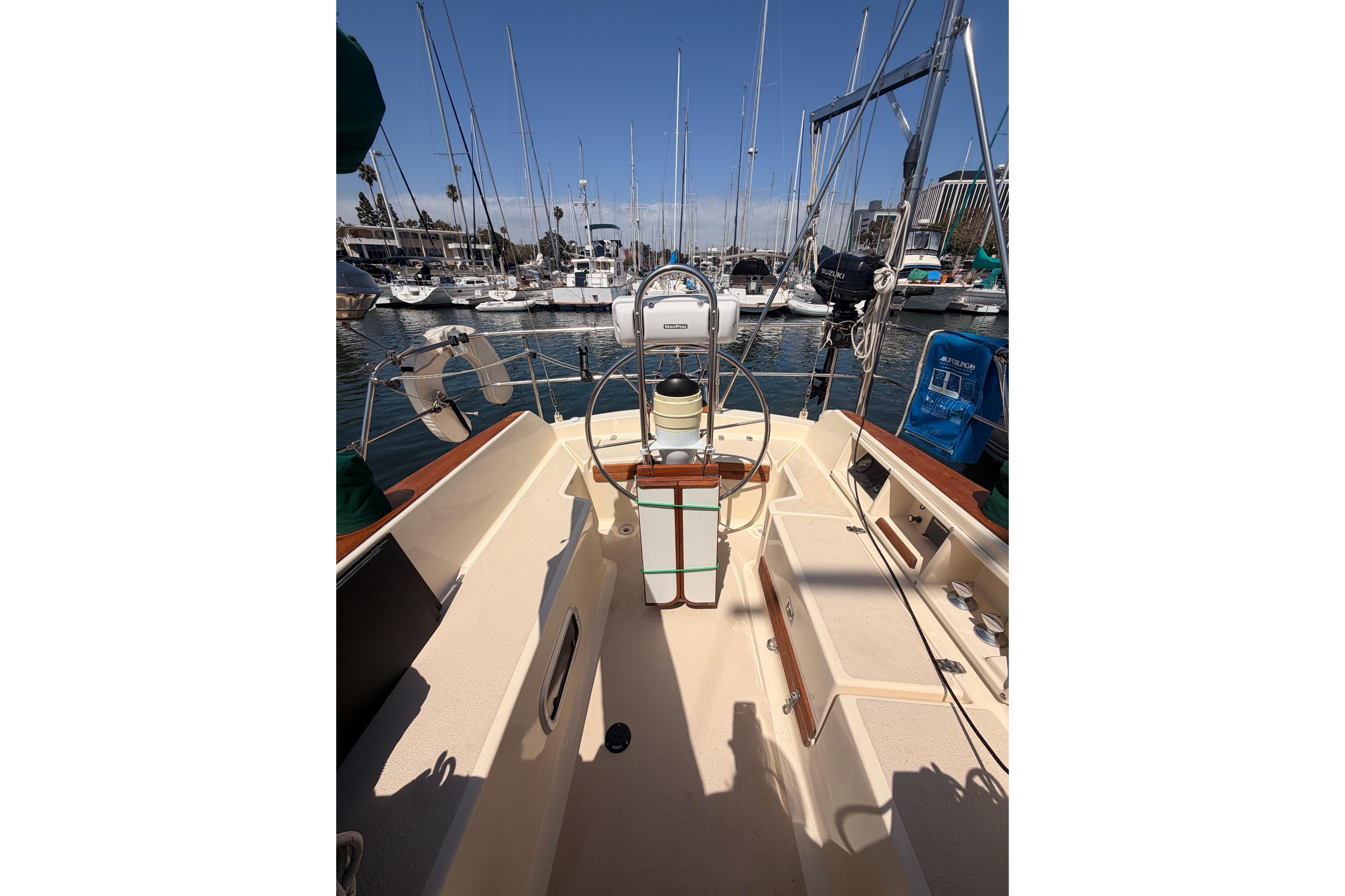 1991 Caliber 33 sailboat cockpit with steering wheel, docked in a marina.