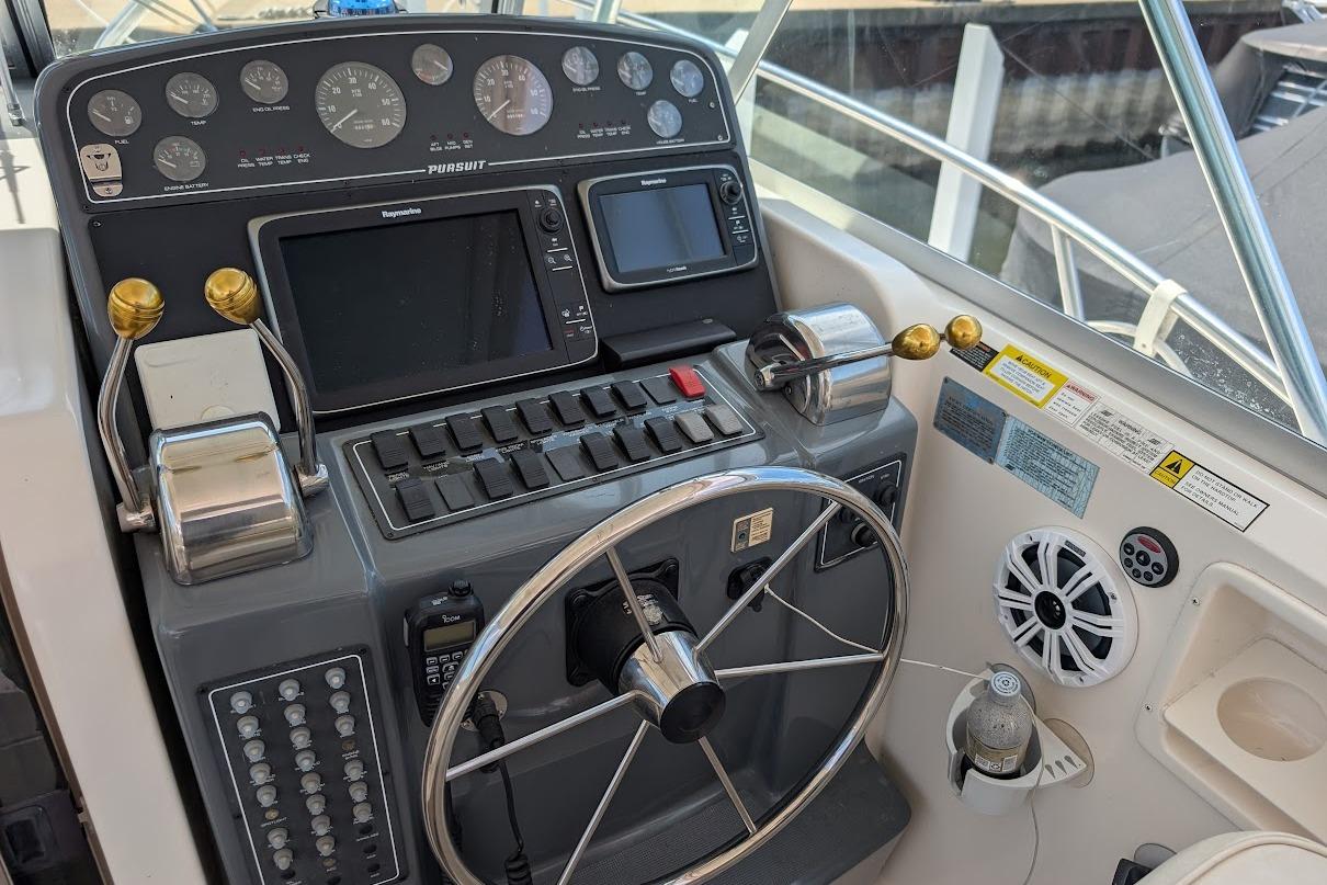 Control panel of a 2000 Pursuit 3400 Express boat with steering wheel and gauges.