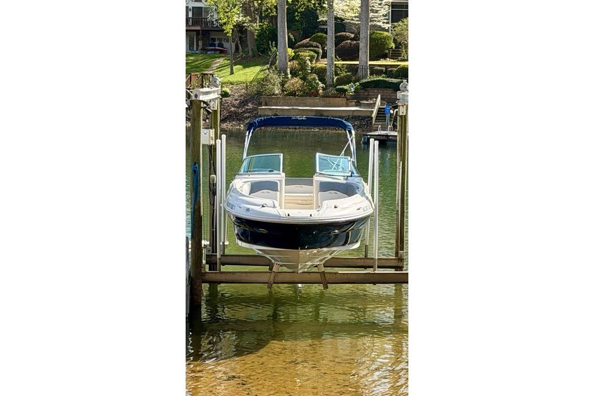 2008 Sea Ray 240 Sundeck boat on lift, docked by lush greenery.