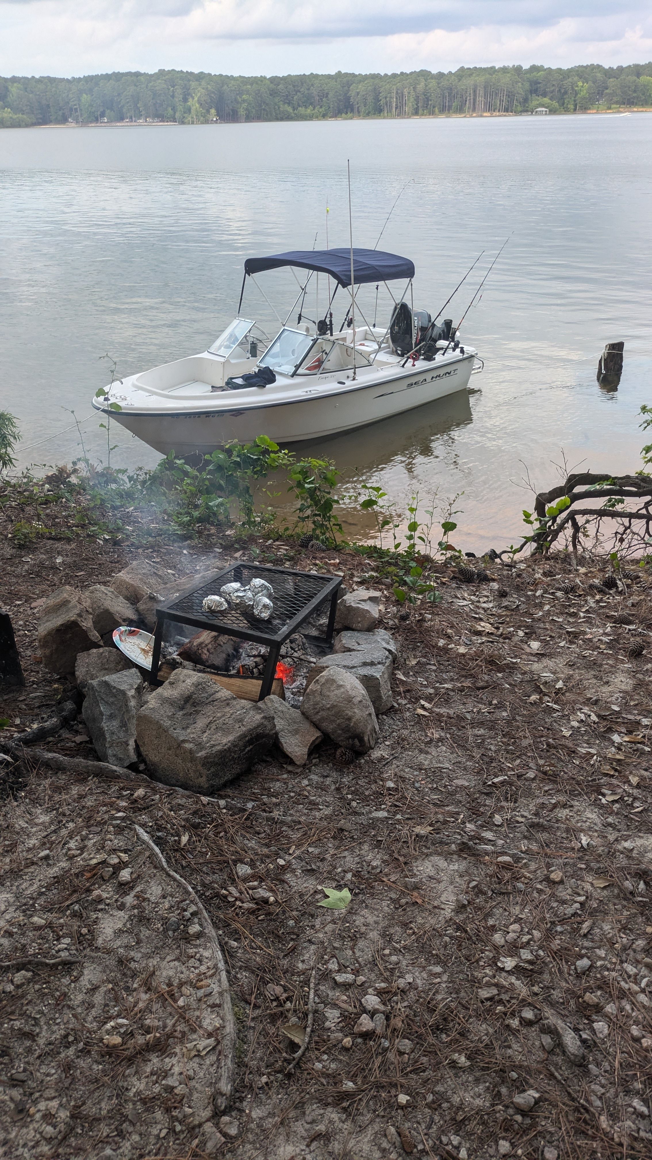Sea Hunt Escape 200 boat by lake with campfire.