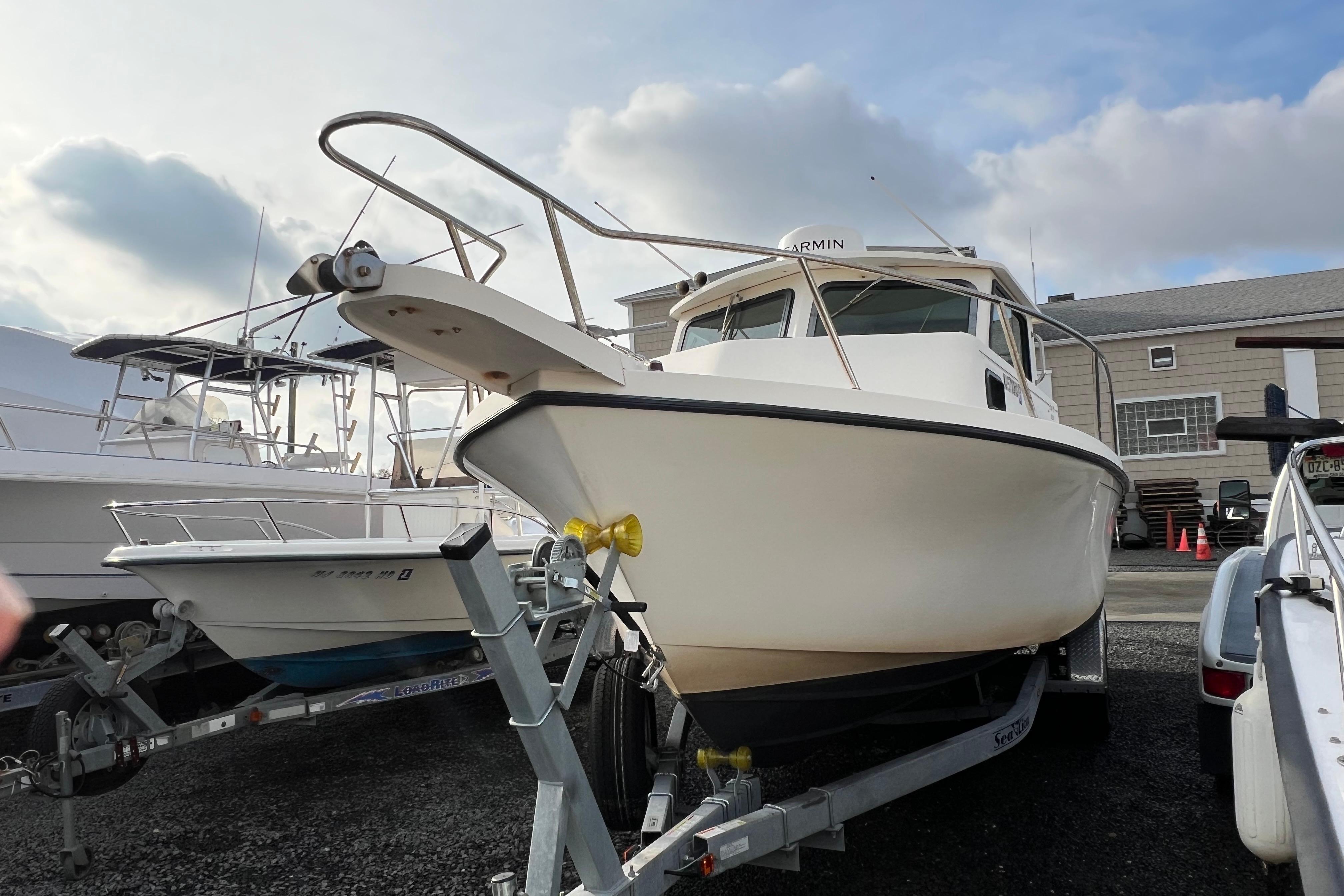 2001 Parker 2520 Deep Vee Sport Cabin boat on trailer, parked outdoors.
