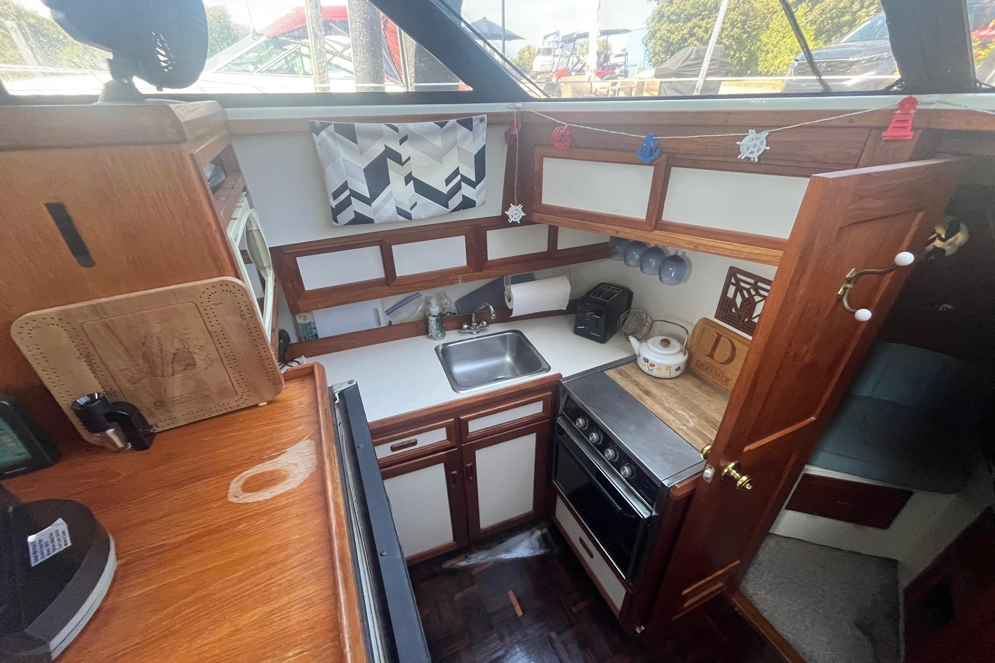 Cozy kitchen in 1990 Cooper Prowler 35 boat with wood cabinetry and compact appliances.