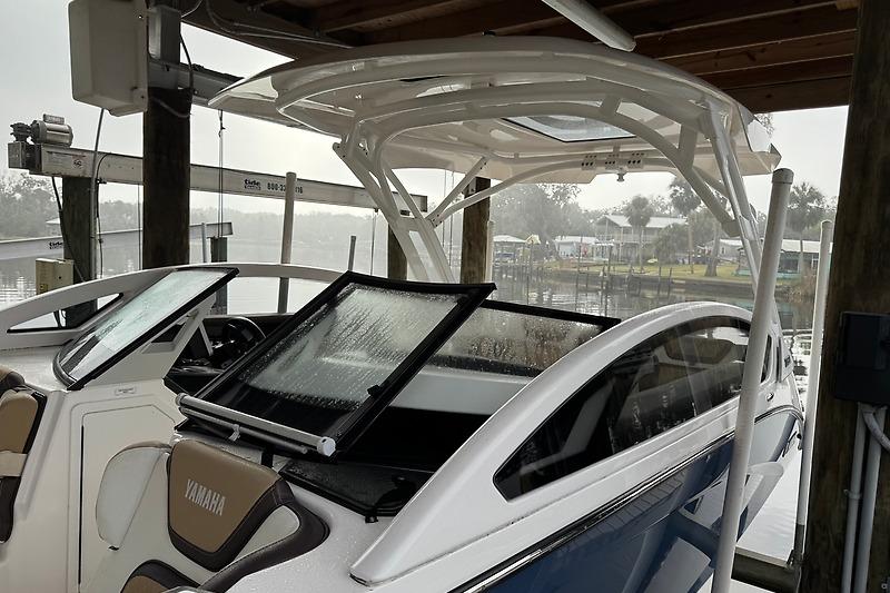 2023 Yamaha 275SDX boat docked under a shelter on a rainy day.