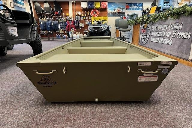 2026 Tracker Grizzly 10 Jon boat displayed in a showroom with various outdoor gear.
