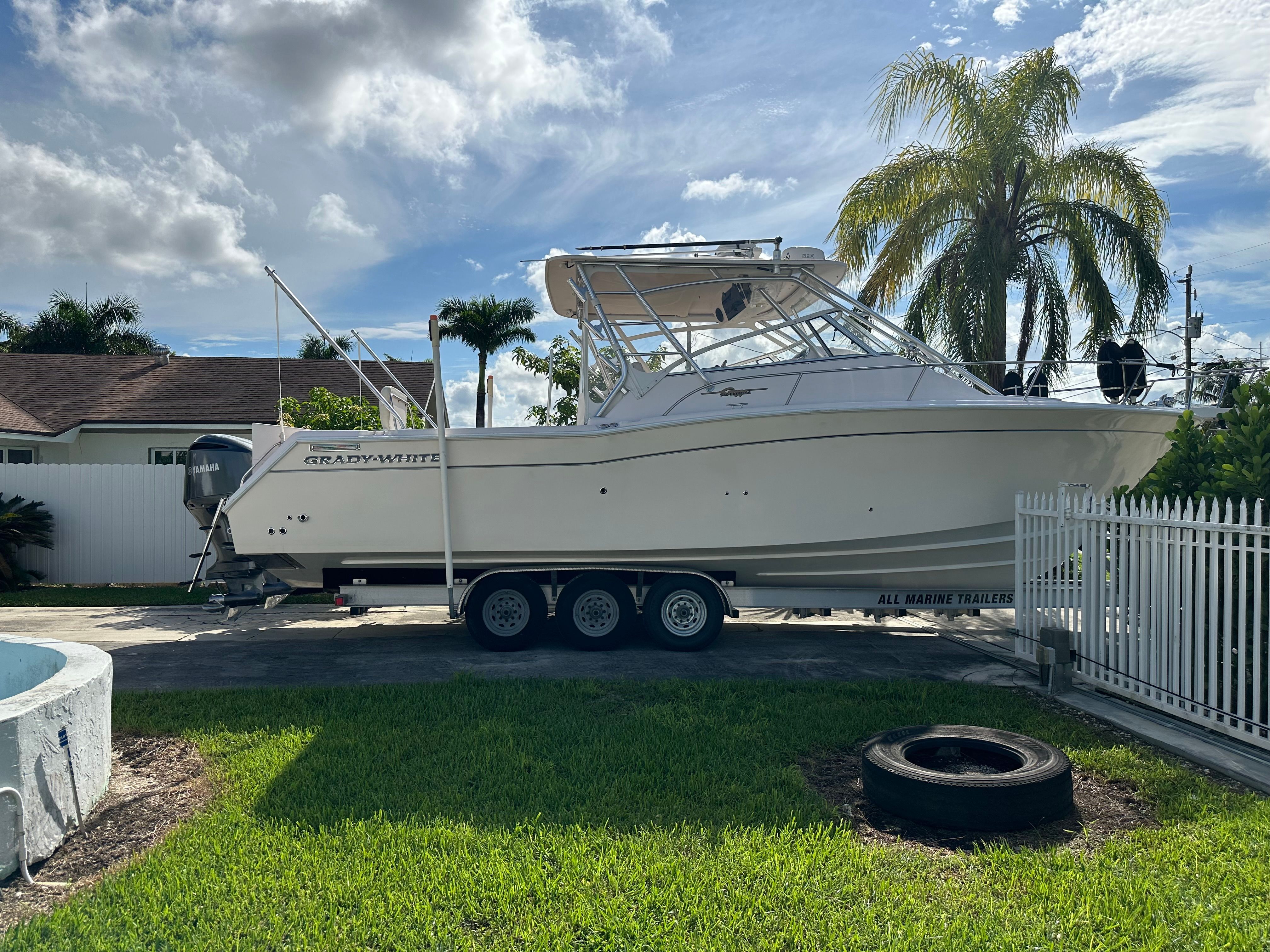 2003 Grady-White Express 330 on a trailer, surrounded by palm trees and a white fence.